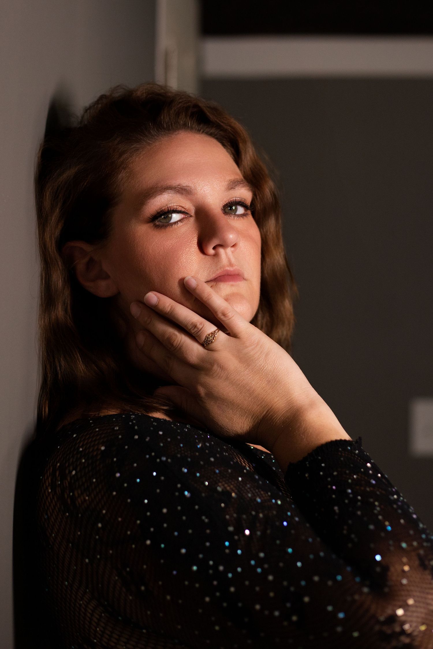 A sequence of dramatic portraits in a dark setting shows a figure in a sparkly black top with various contemplative poses.