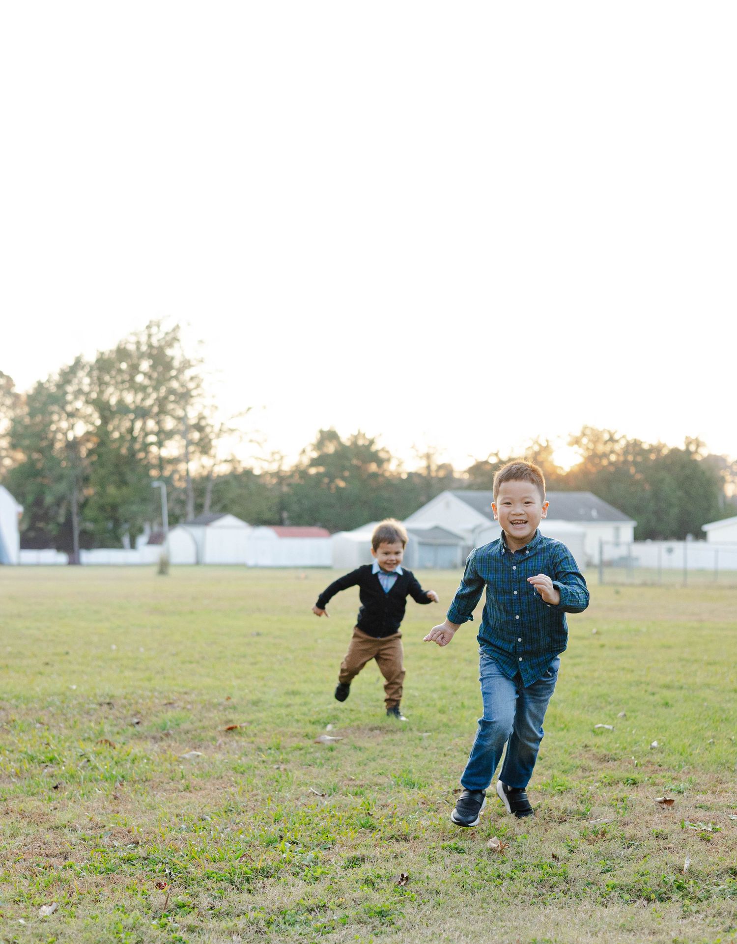 Children running and playing in an open field during golden hour.