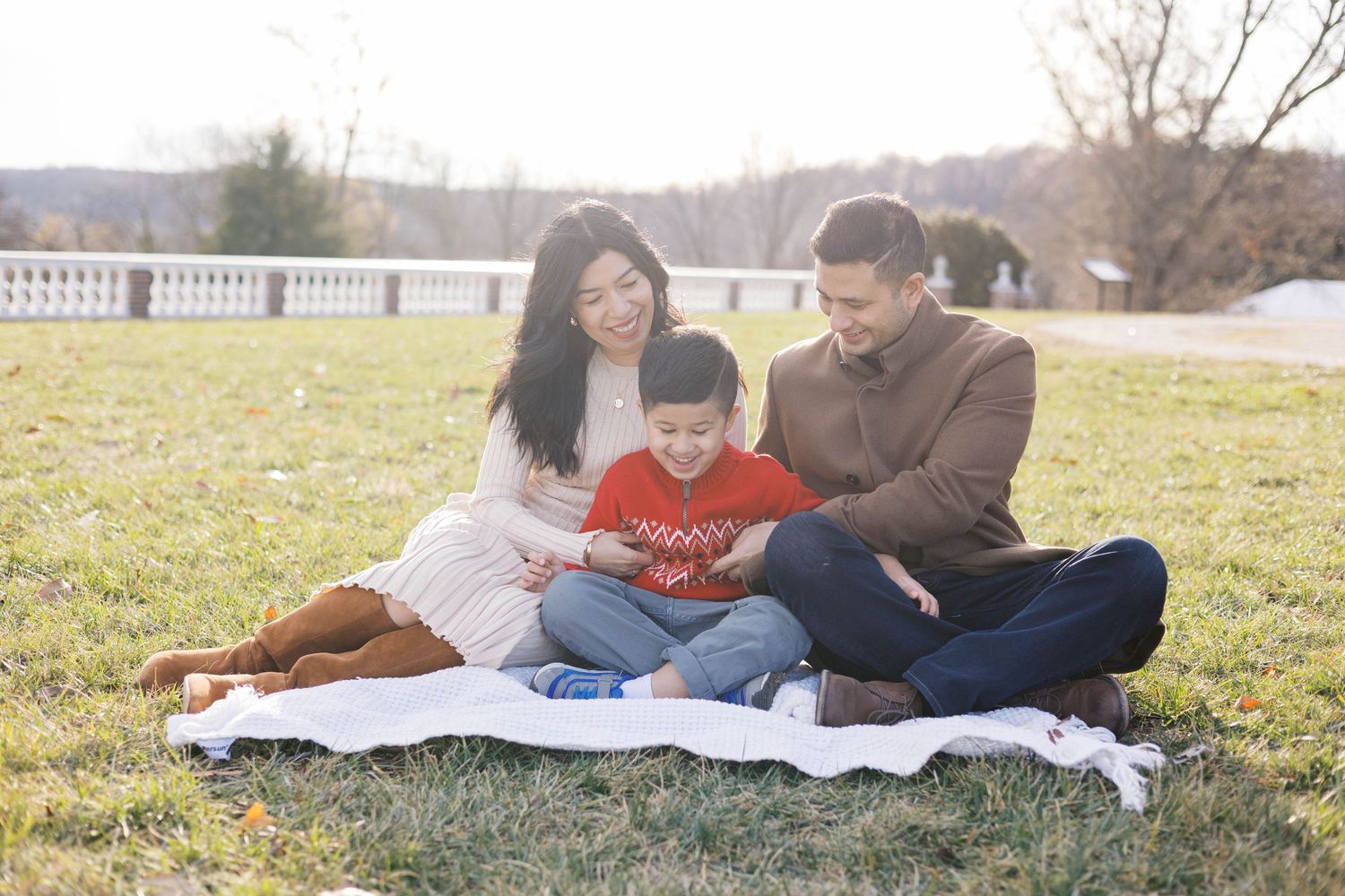 Family members relax together on a blanket during an outdoor photo session.