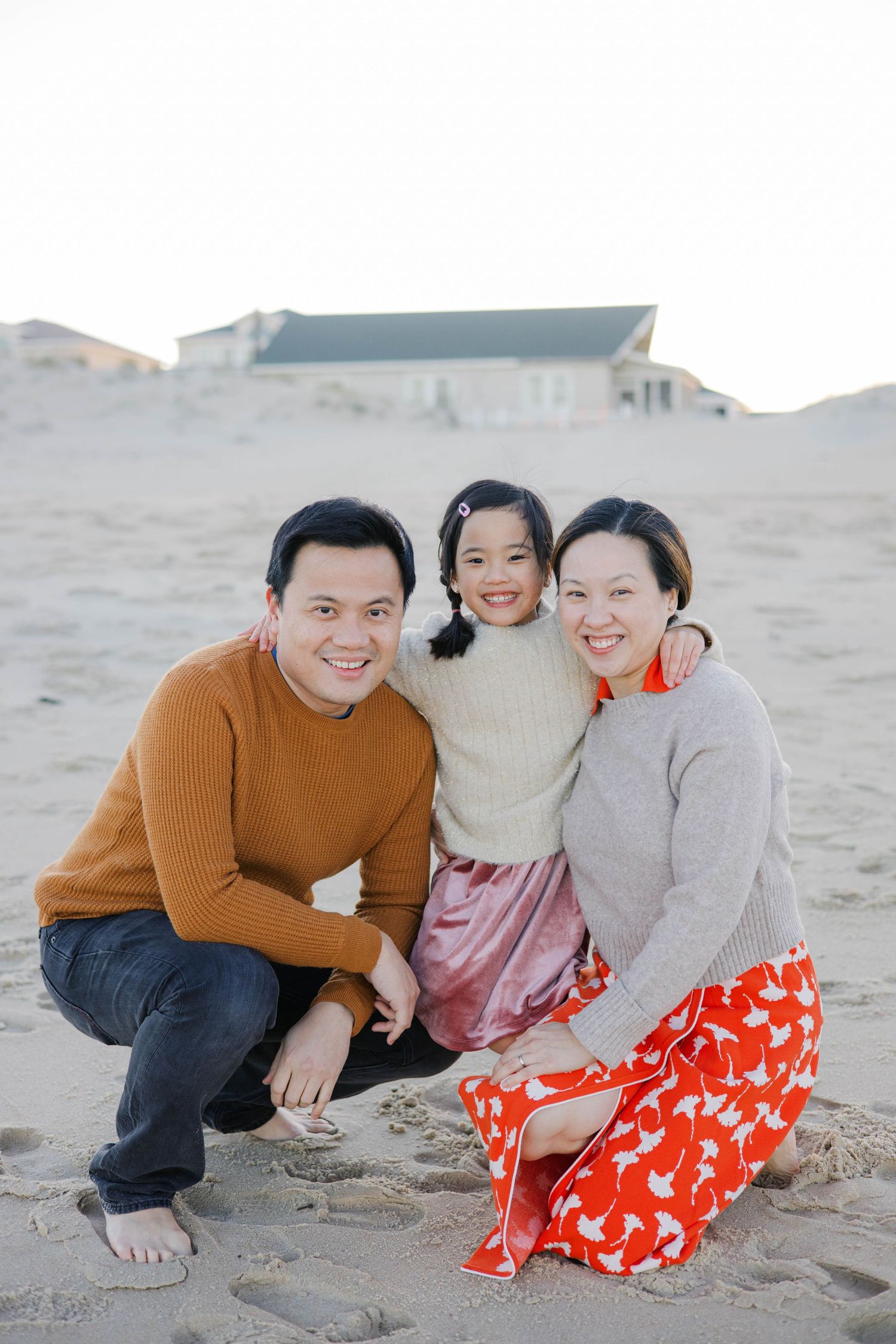 Relaxed family beach portraits with warm autumn colors and red patterned dress.