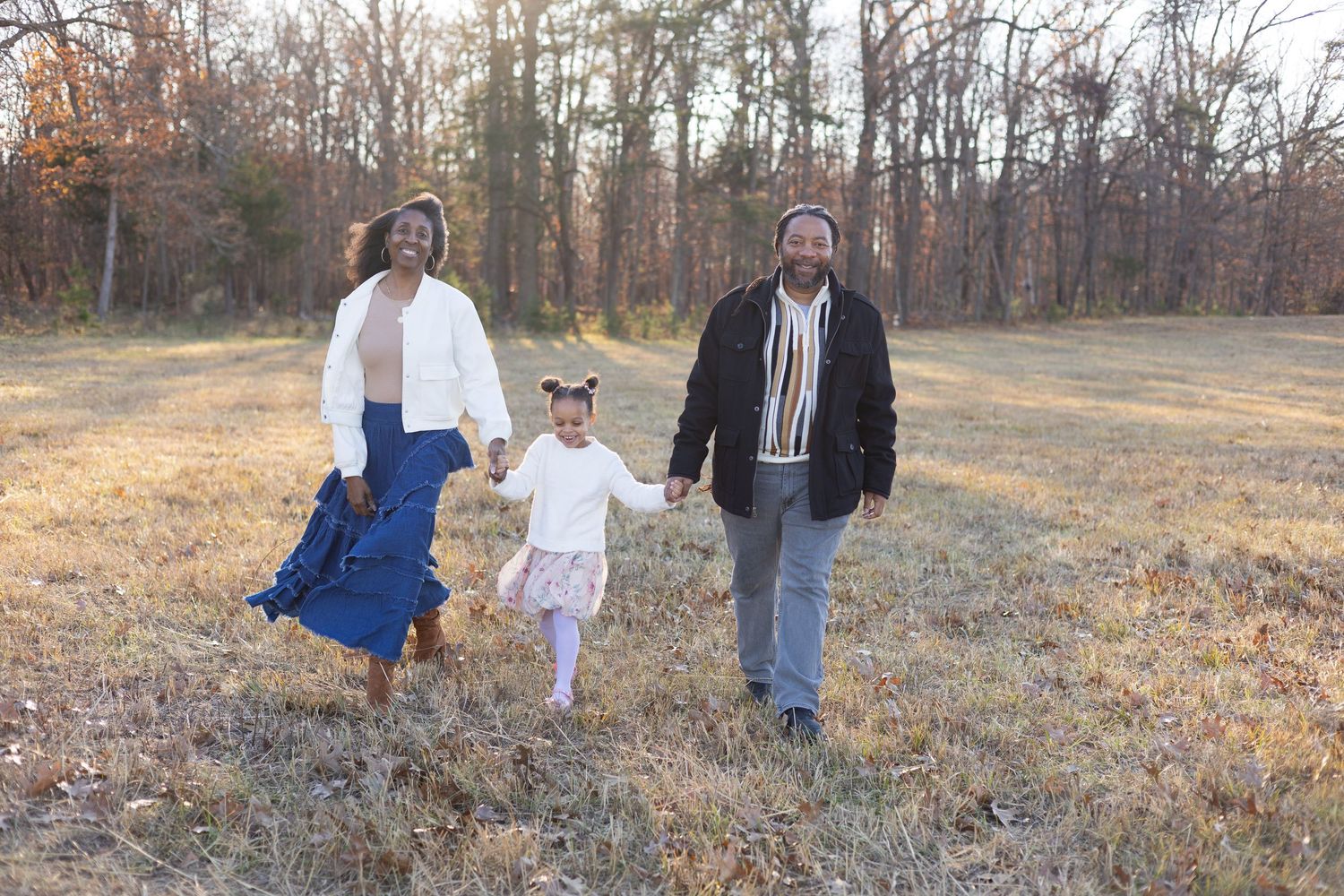 Family enjoying quality time together while sitting in a field during golden hour.