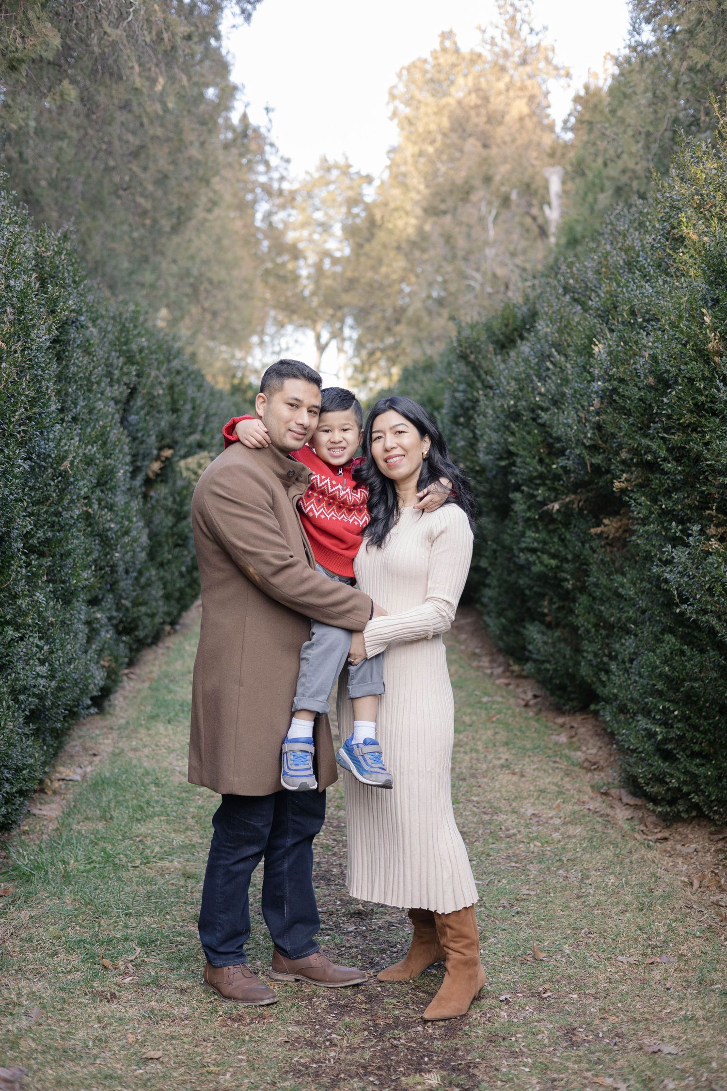 A family portrait session among evergreen trees during autumn.