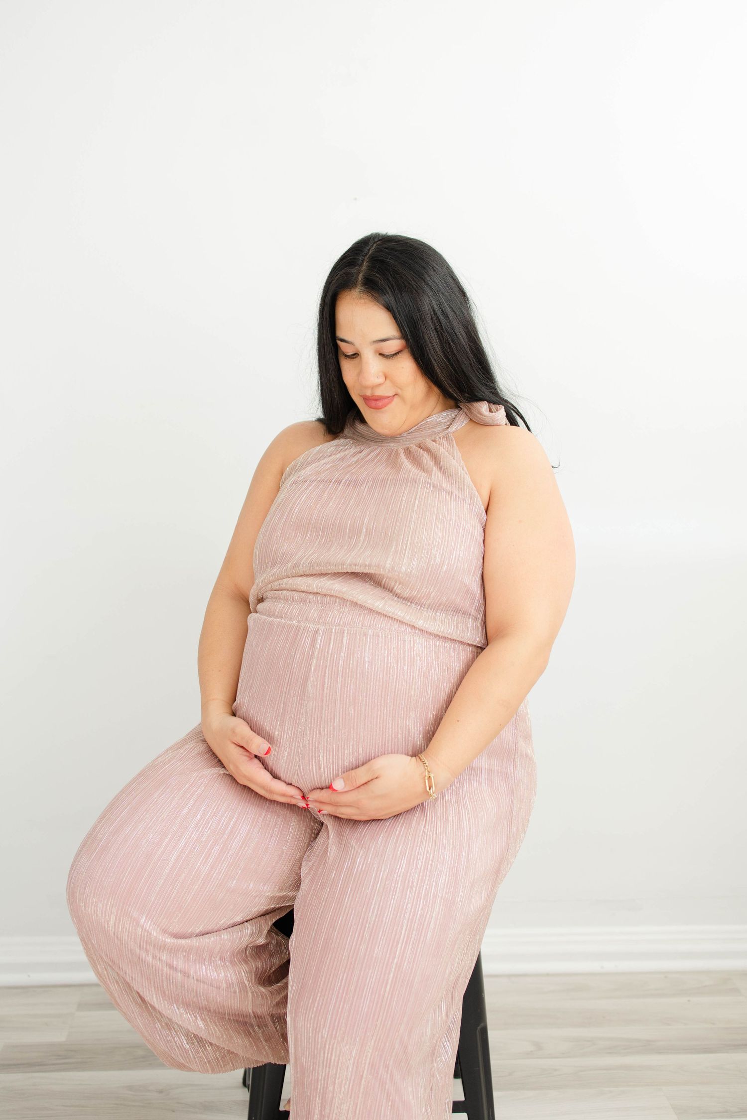 Pregnant woman in pink dress poses solo for artistic maternity portraits.