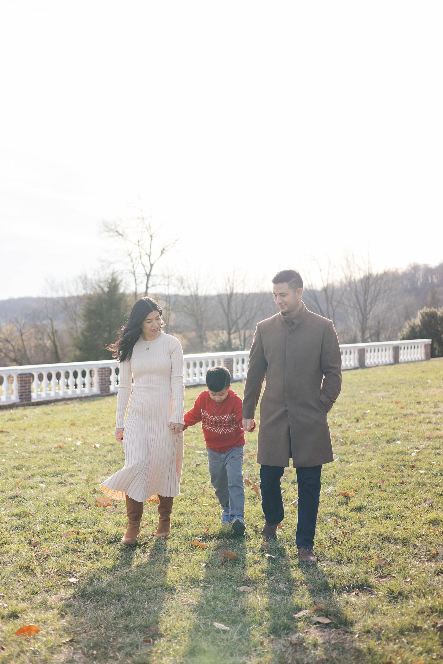 Family walking together on grassy hill during golden hour.