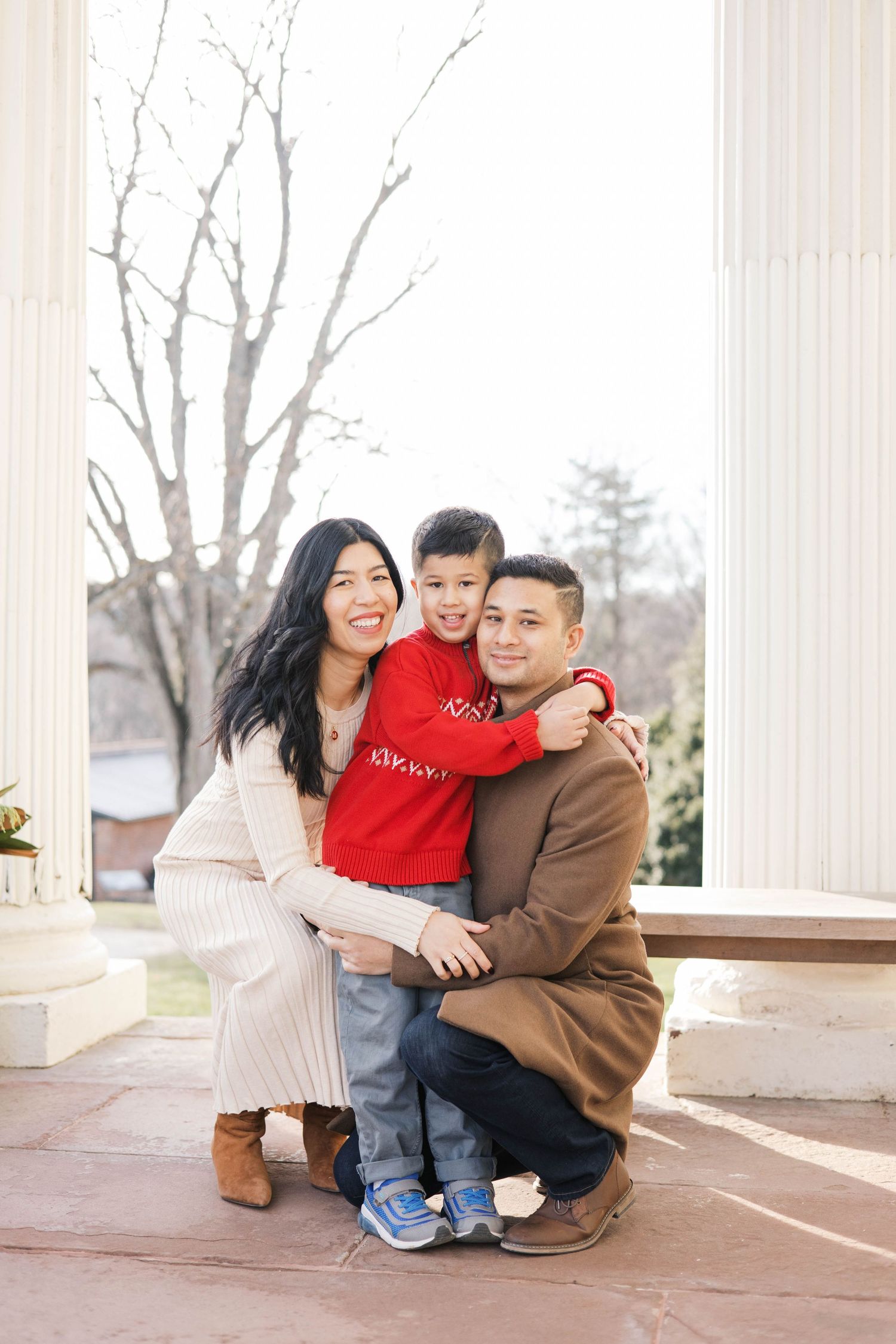 Family embracing and laughing together on a columned porch.