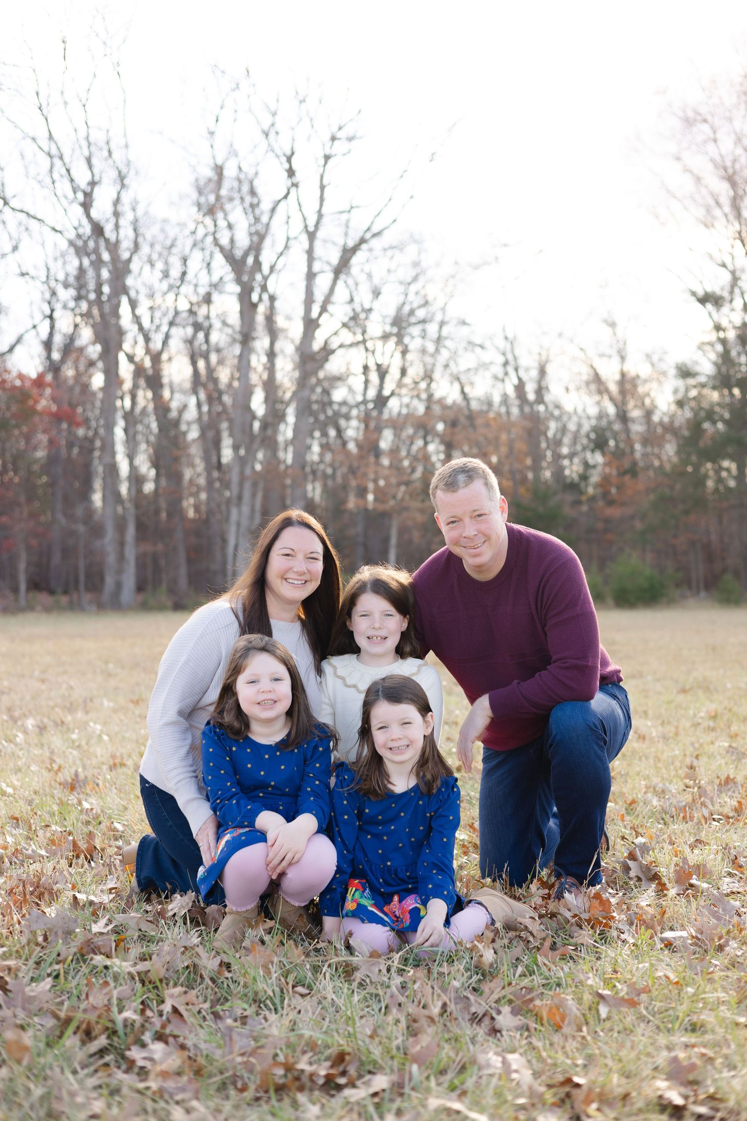 Family sitting together in a rustic autumn field during golden hour.