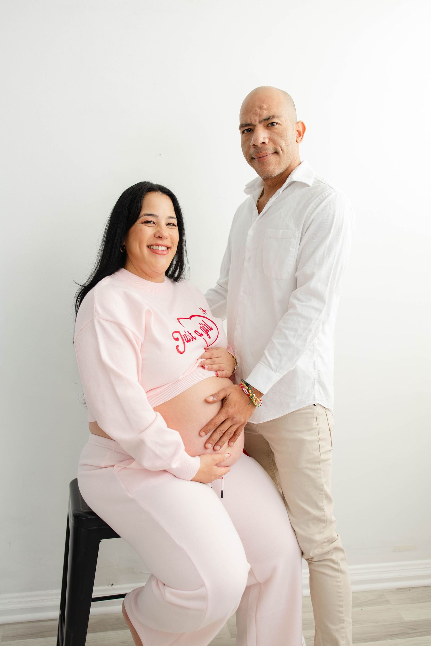 Modern maternity session featuring couple in coordinated pink and white outfits.