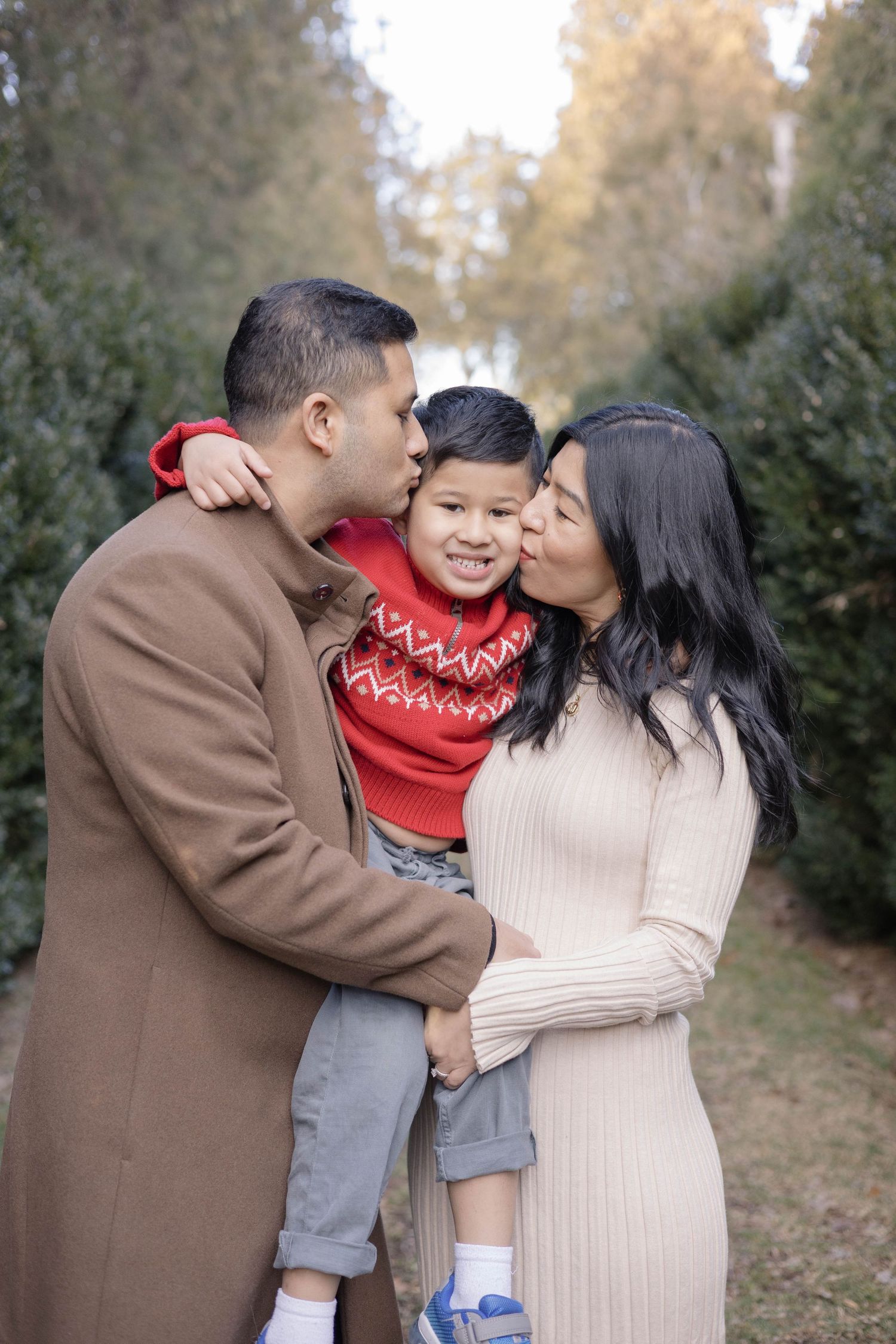 Family shares tender kisses and embraces during outdoor autumn photo session.