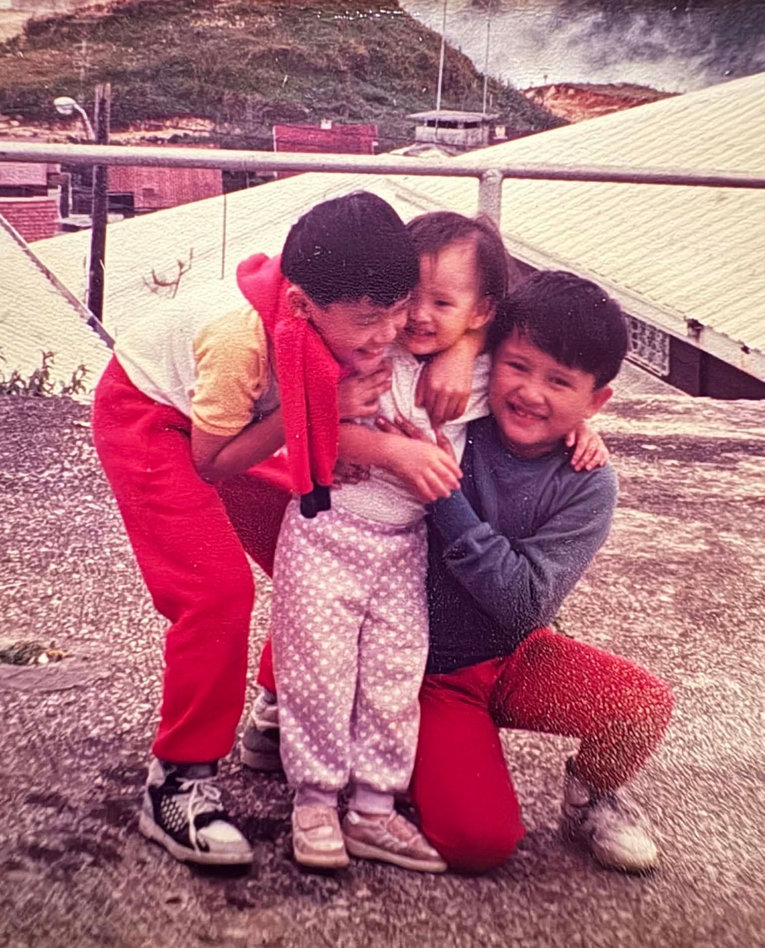 Retro photograph showing children embracing and laughing together outdoors.