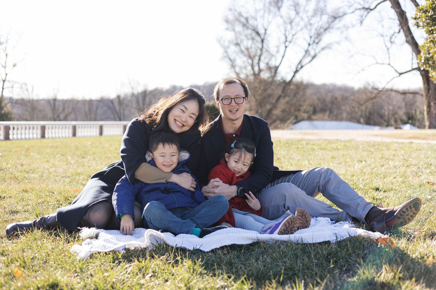 Family members lying together on a blanket outdoors during an autumn photoshoot session.