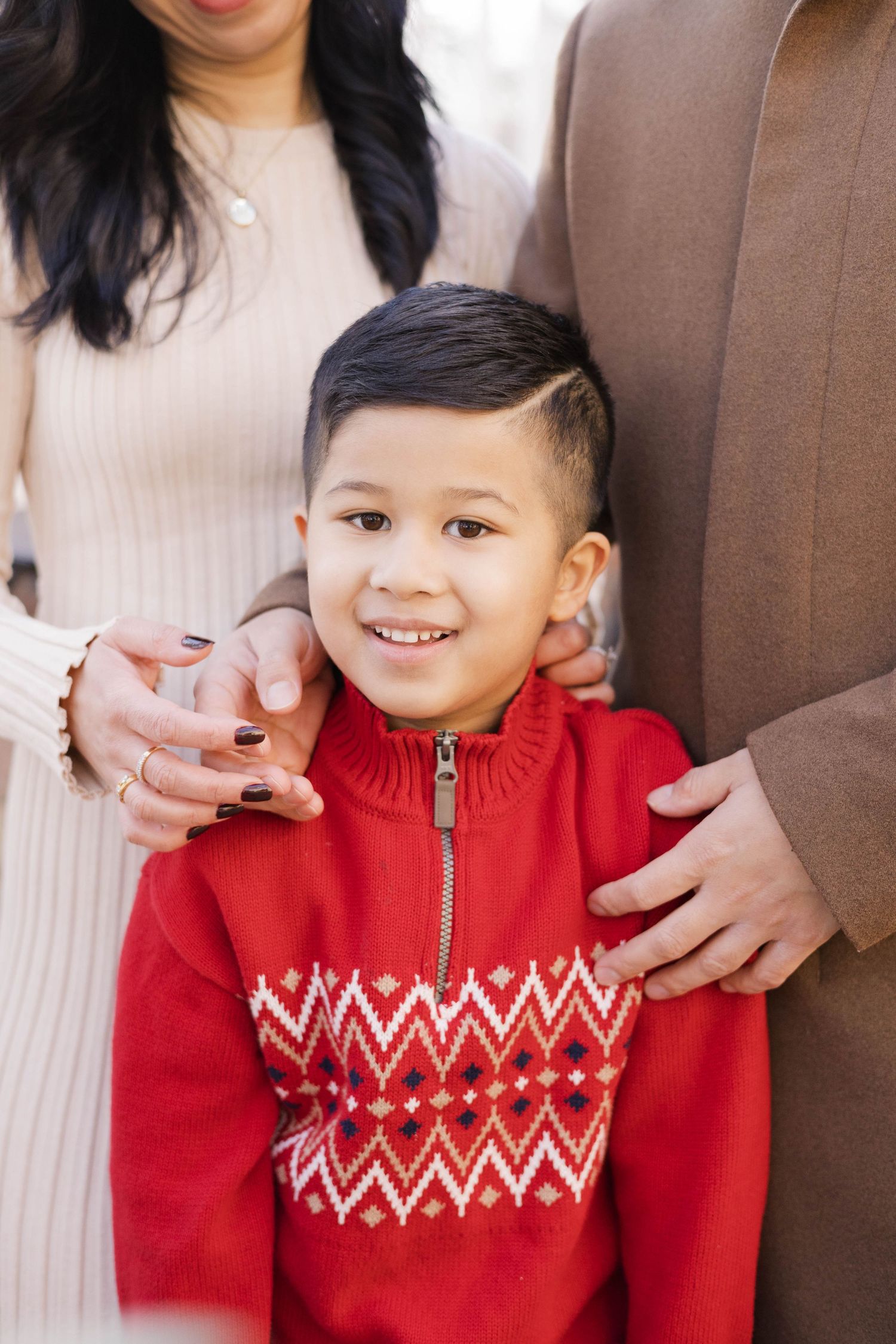 Close-up portrait showing a red festive sweater with white geometric pattern during a winter photo session.