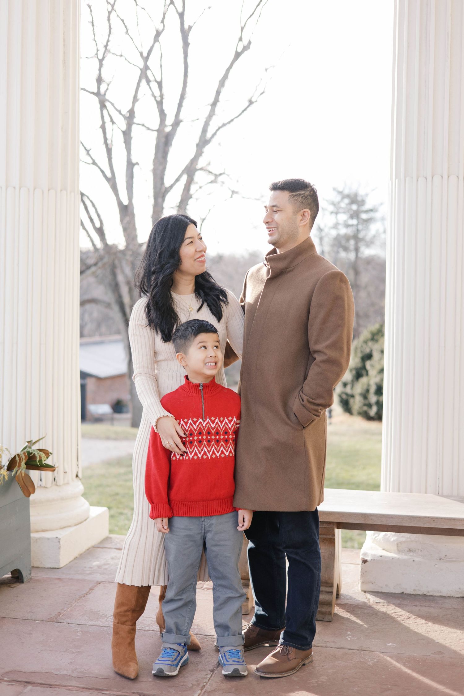 Family sharing candid moments between elegant white columns.
