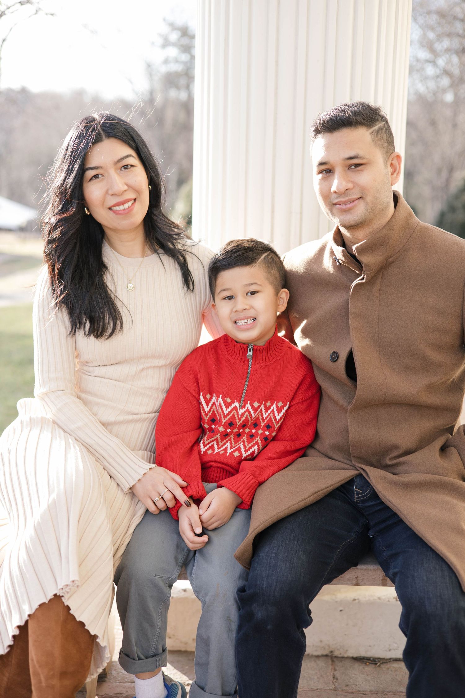 Family sitting together on porch steps between white columns.