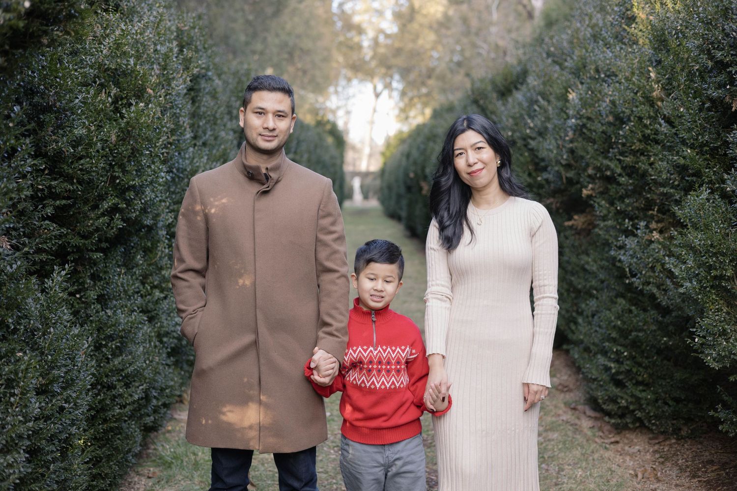 A family stands together on a tree-lined path during an autumn photo session.