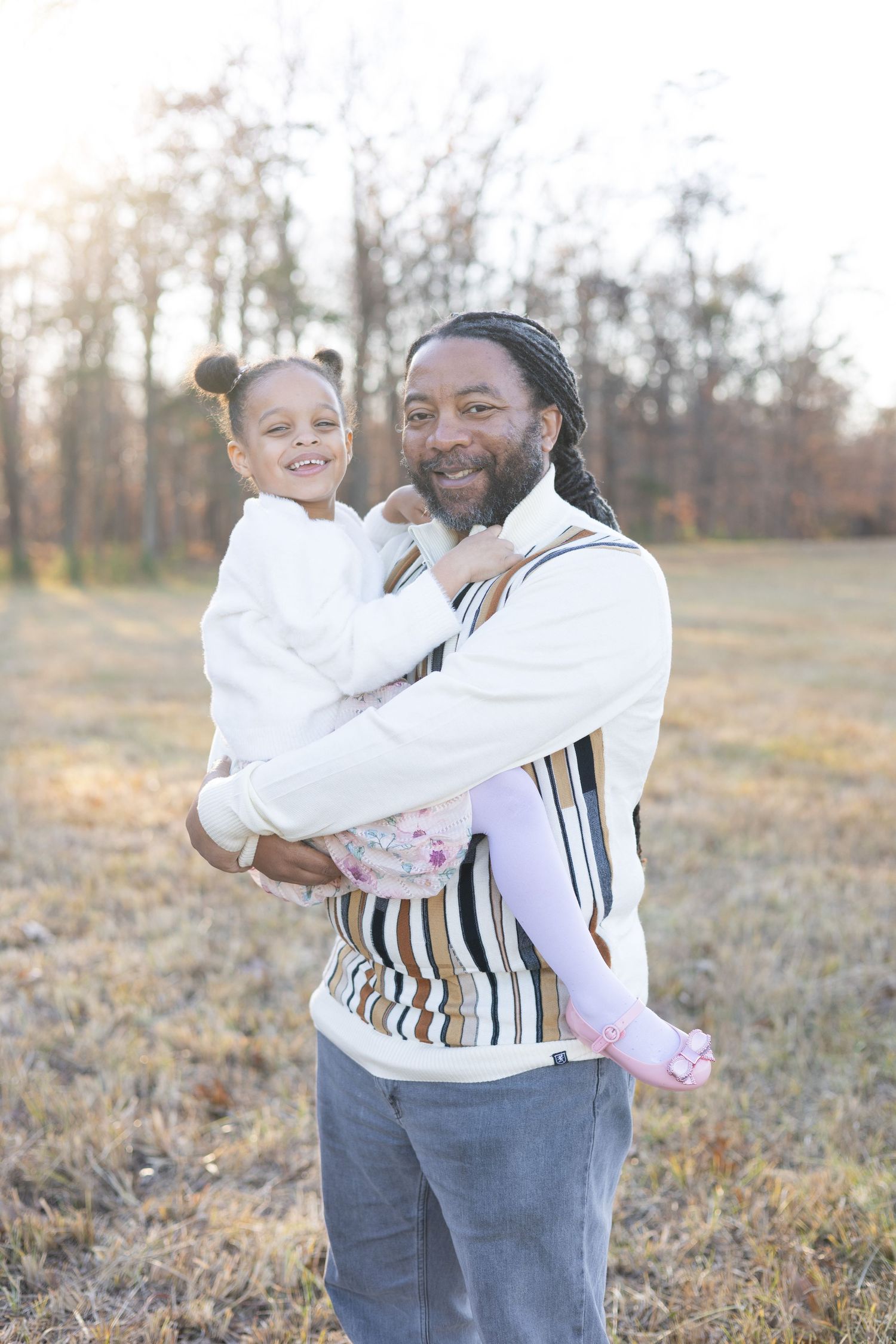 Family wearing coordinated white and striped outfits posing in autumn field.