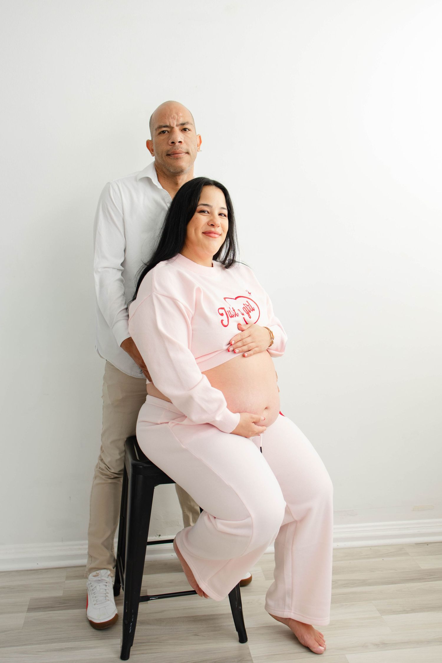 Relaxed maternity portraits with couple in pink and white outfits.