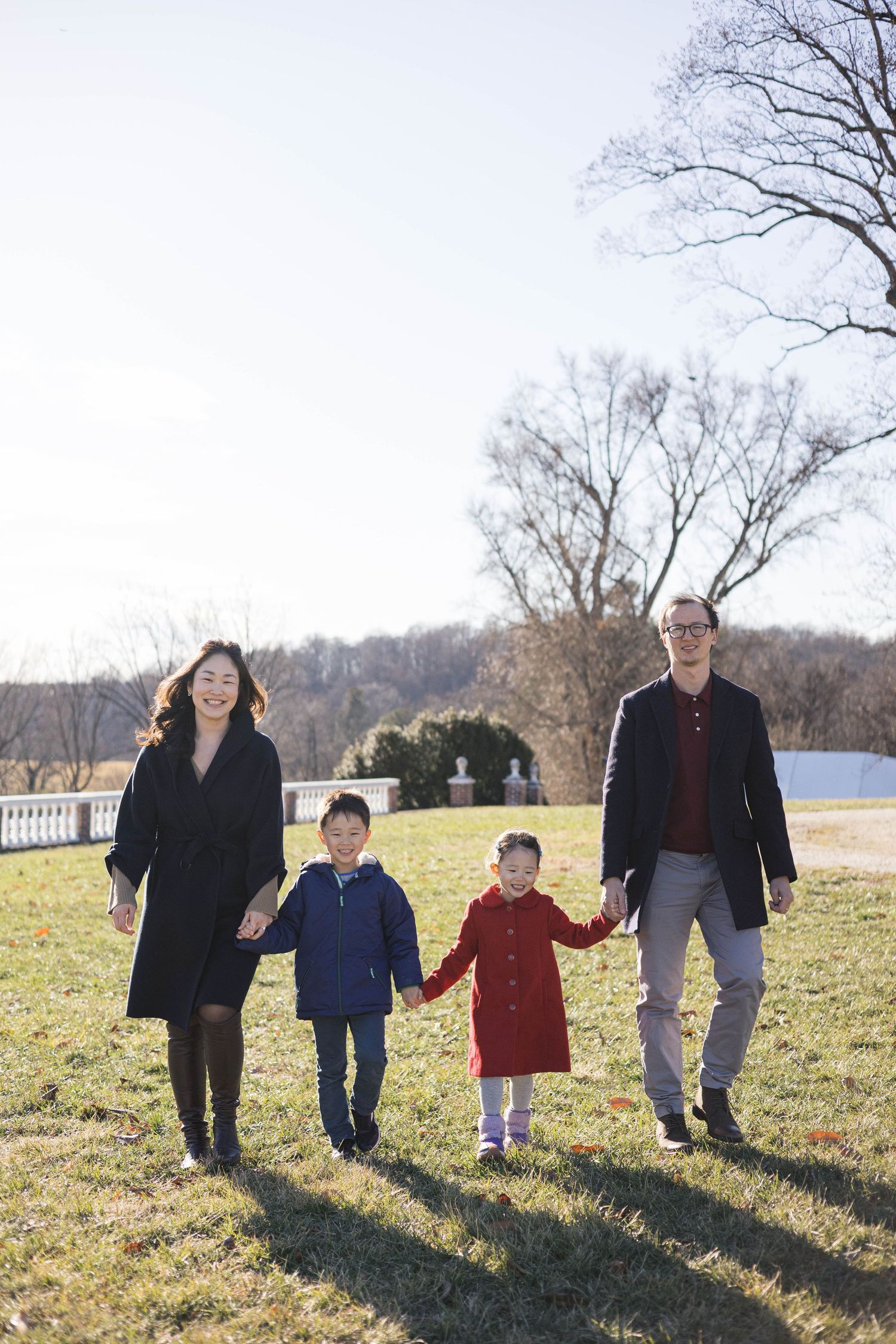 Family members walking in a line across a sunny hillside while holding hands.