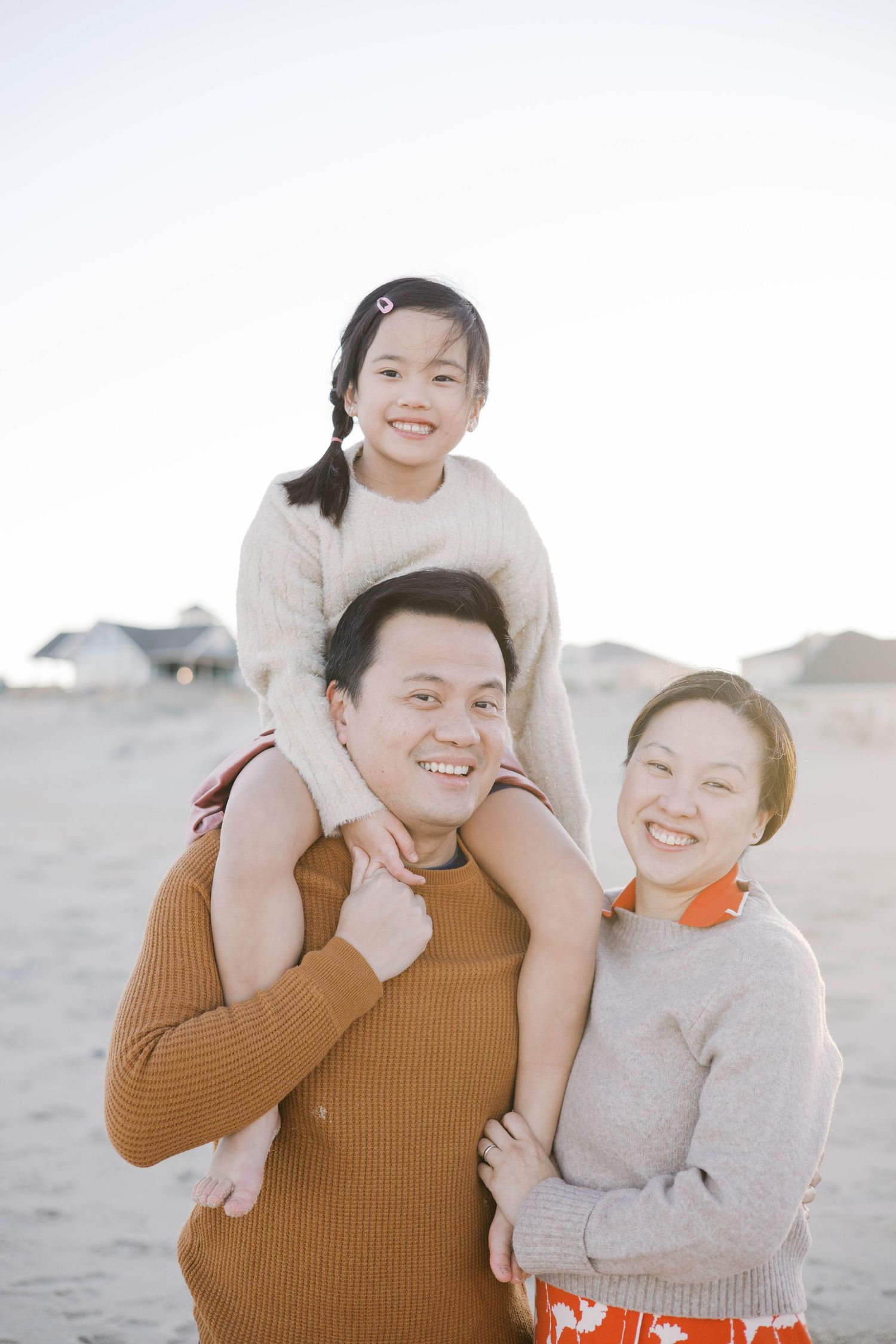 Family sharing joyful embraces on beach during golden hour.