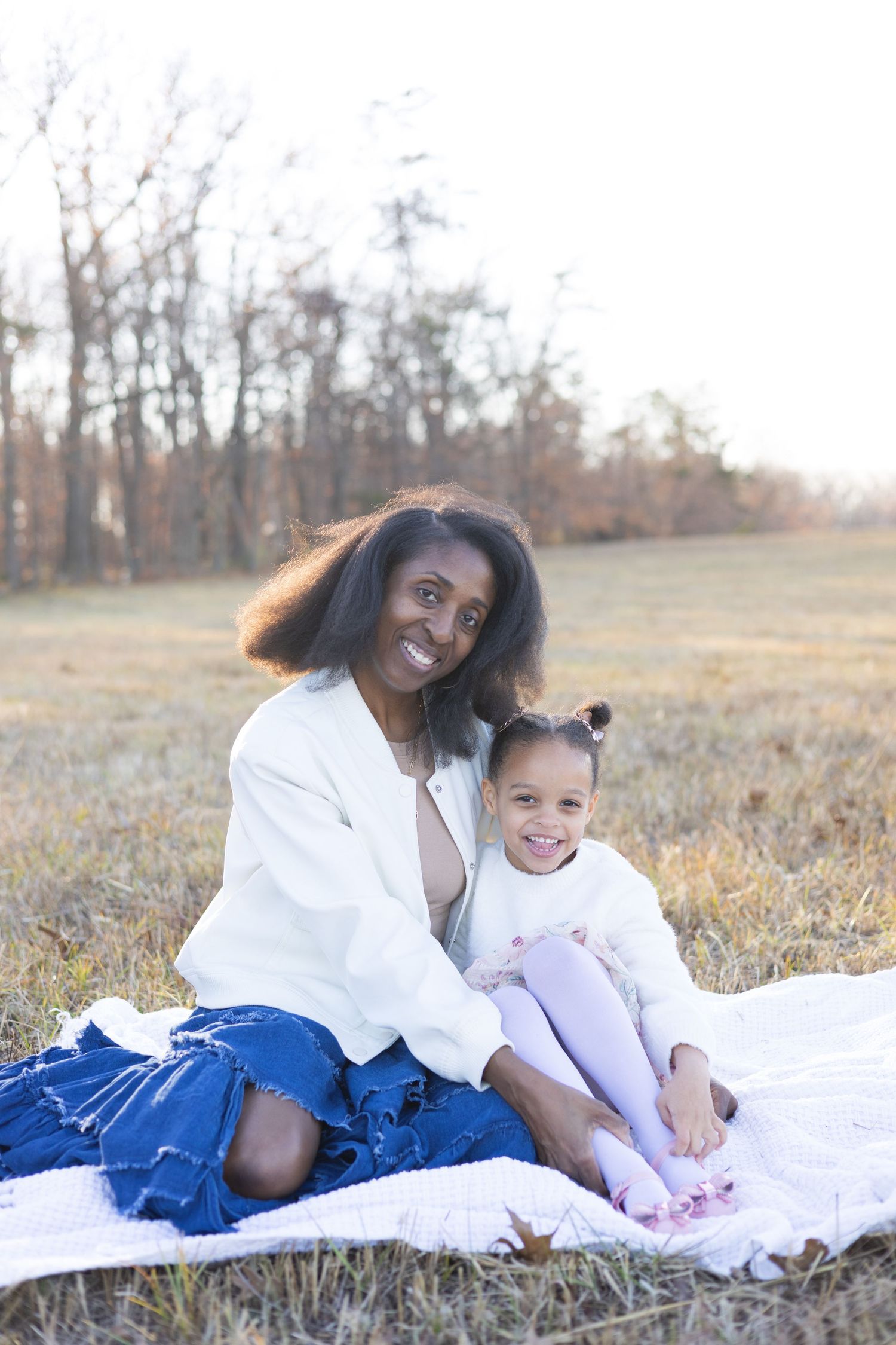 Sweet family portrait session on white blanket in autumn field setting.