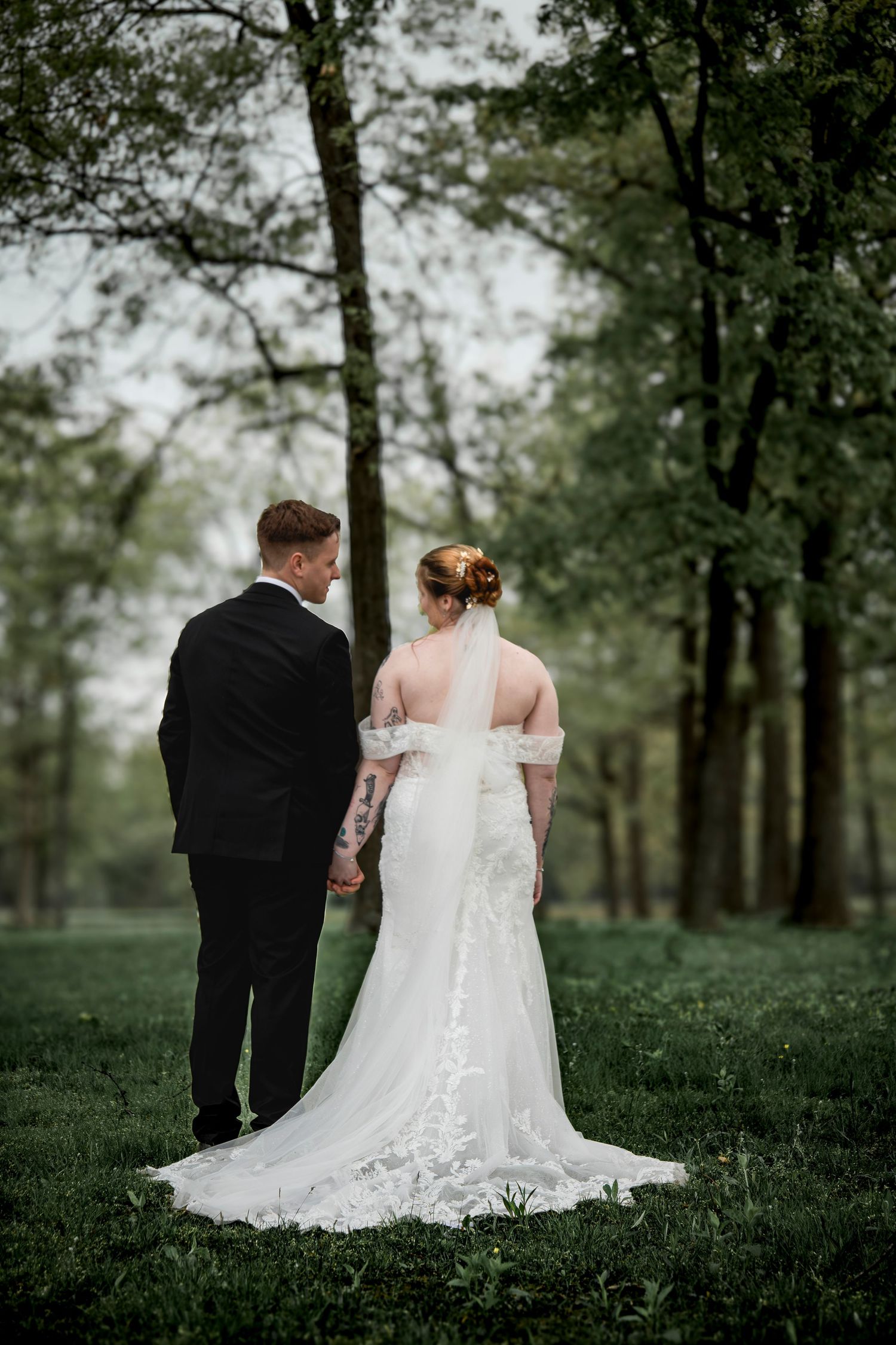 Wedding couple photographed from behind walking through a scenic wooded setting.