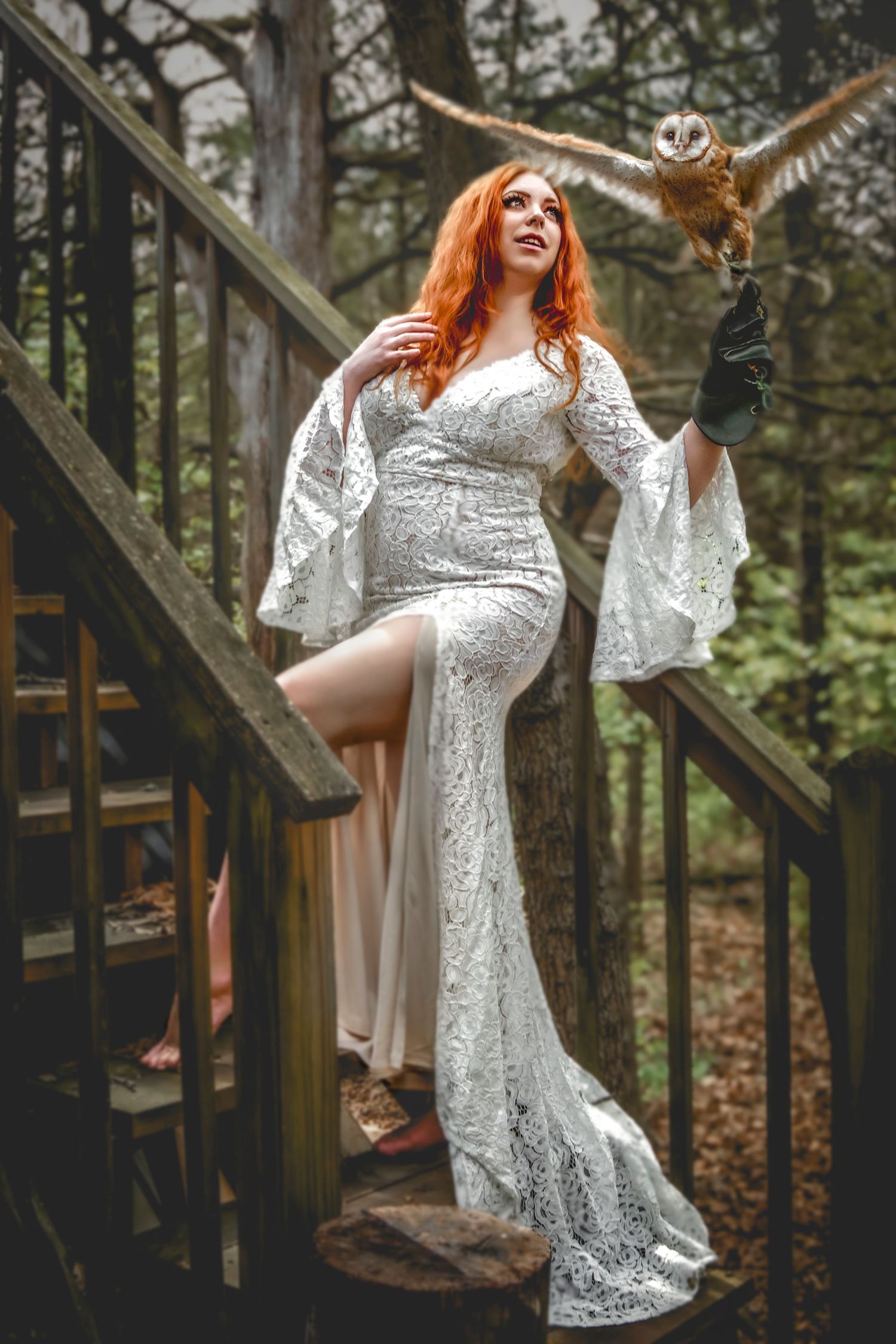 Ethereal maternity photoshoot in white lace dress on forest stairs.