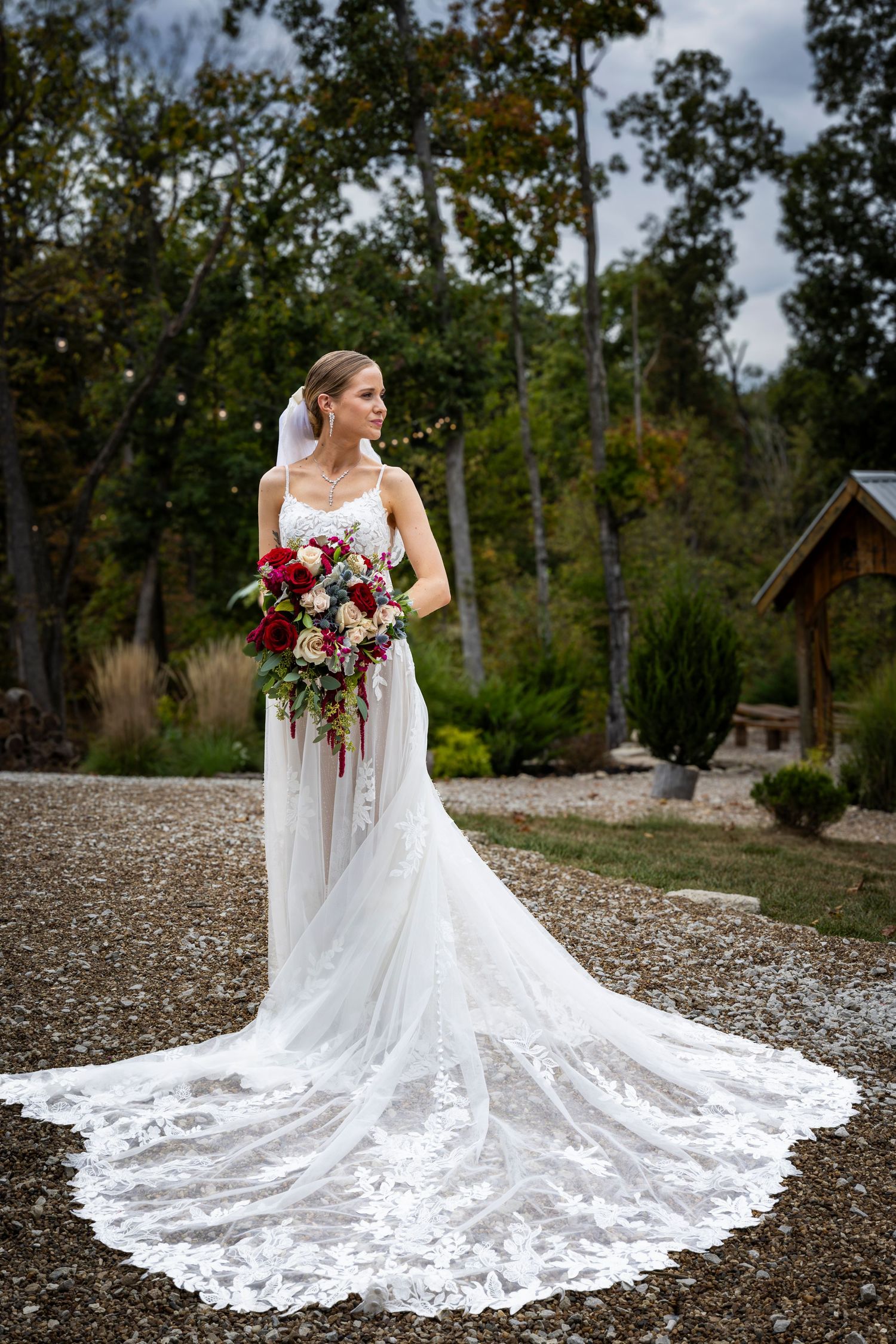 Stunning lace wedding dress with cathedral train displayed on gravel path.