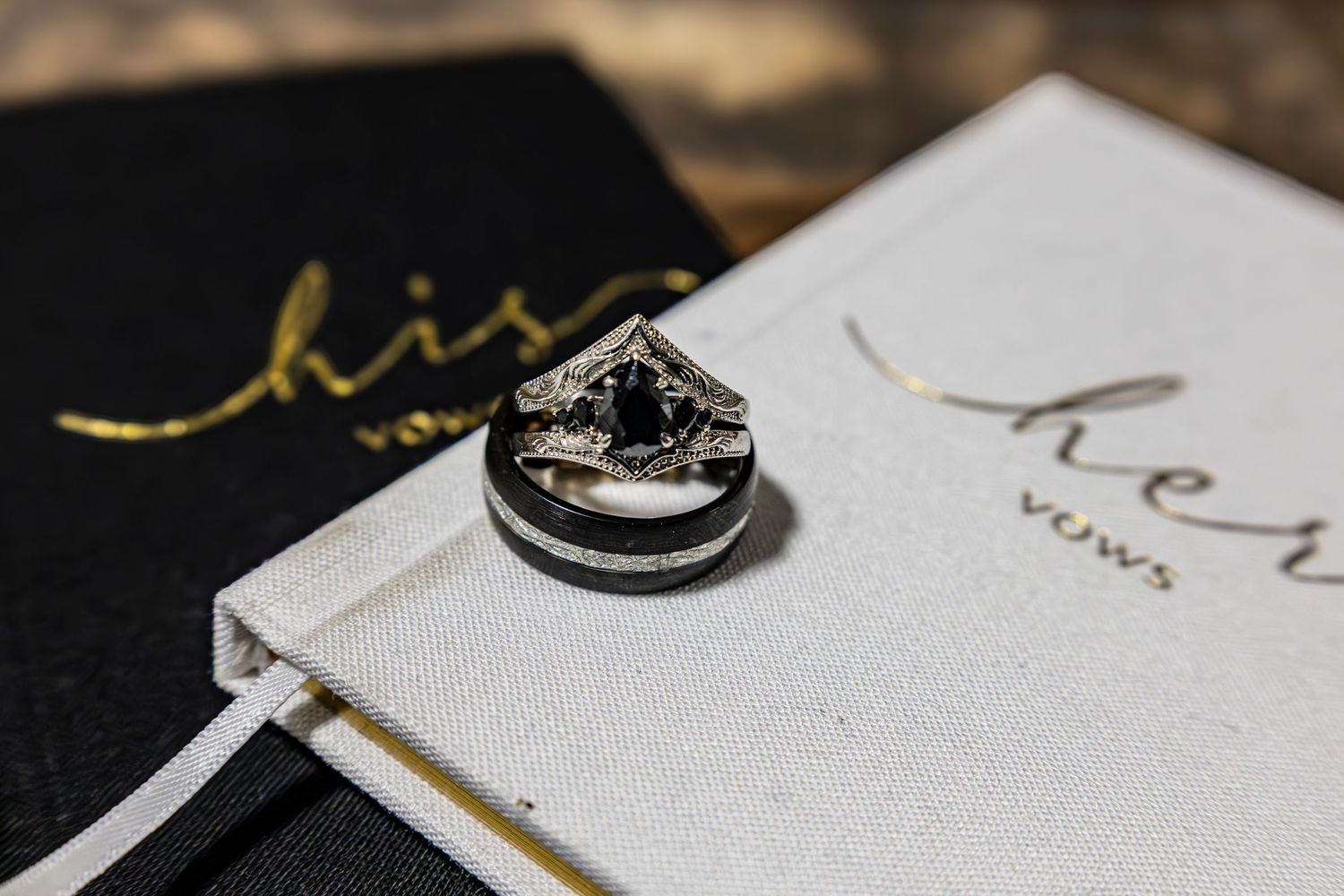 Wedding rings and vow book details captured in elegant black and white.