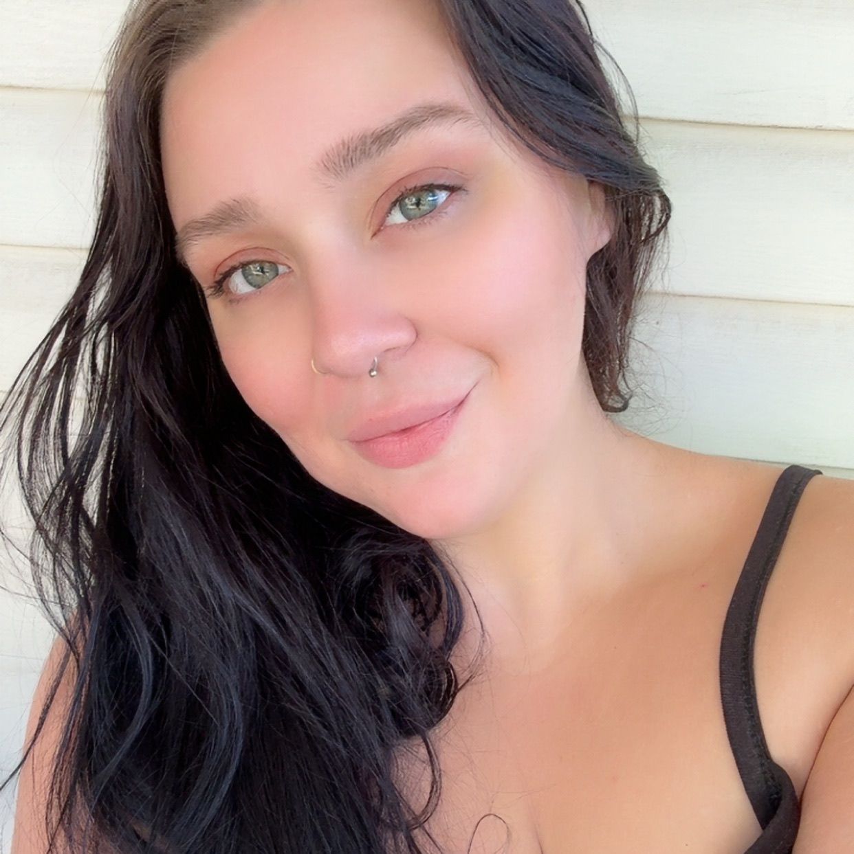 Close up selfie portrait with natural lighting against white siding.