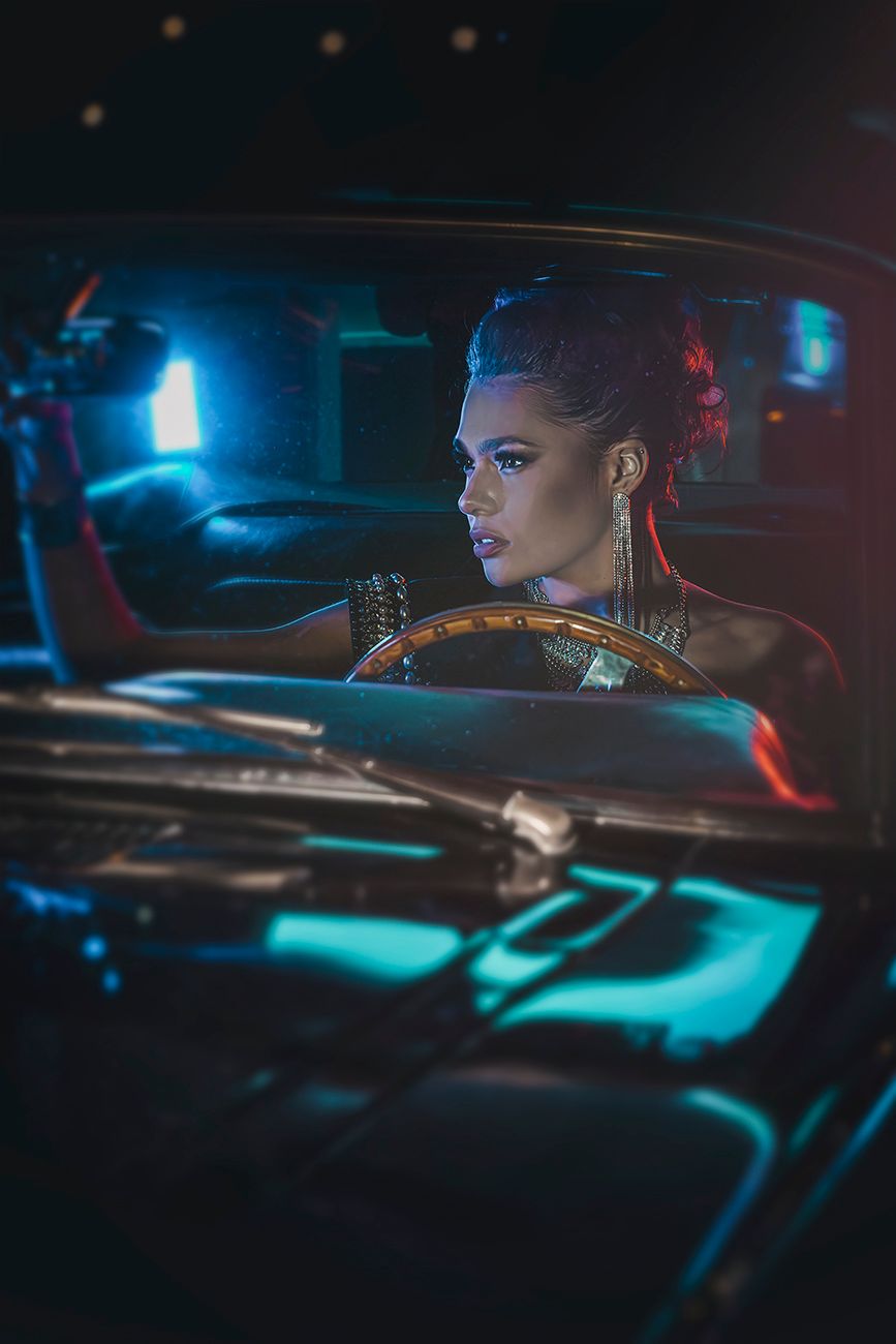 Retro-styled automotive photography with dramatic blue lighting and dashboard details.