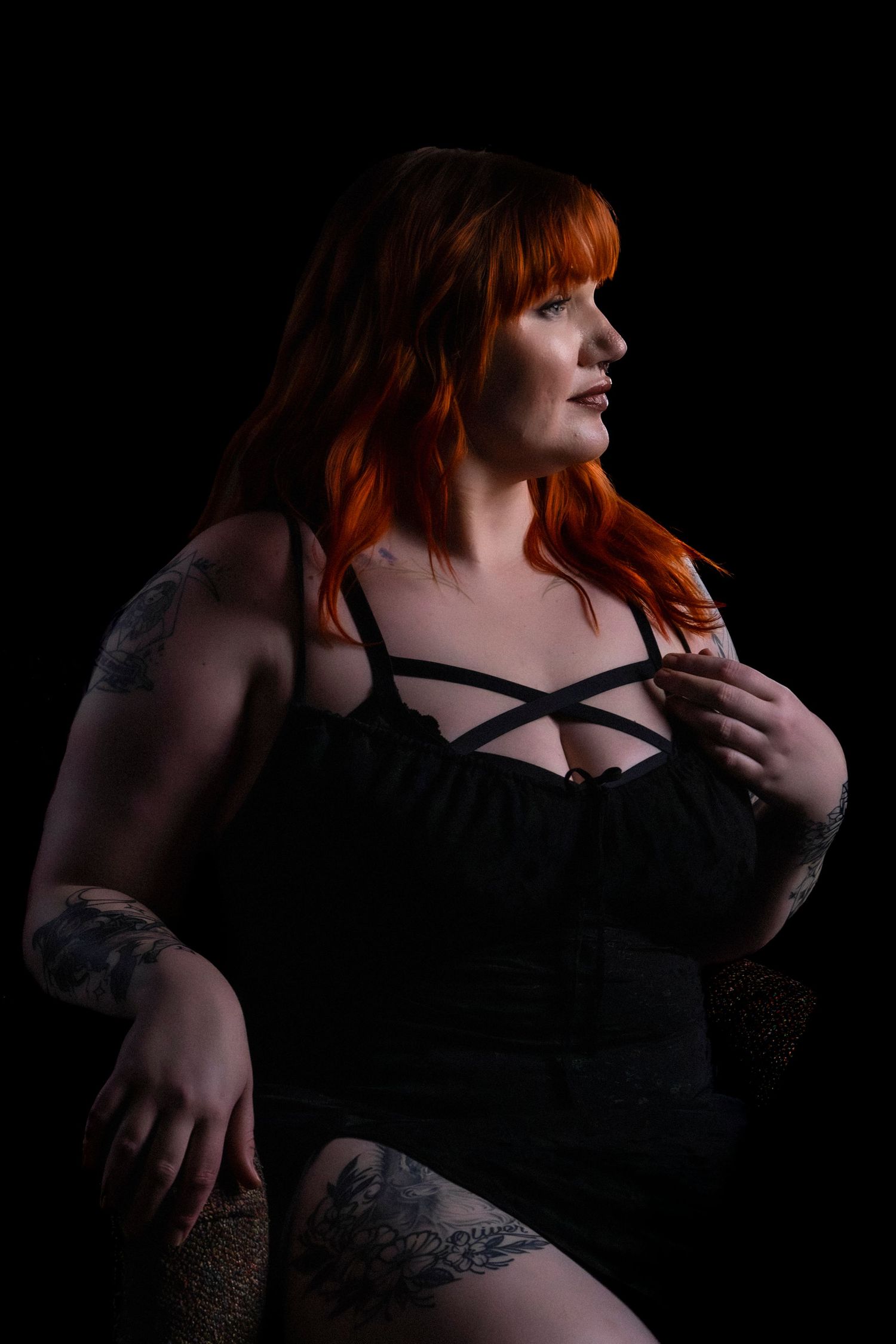 Moody boudoir photography with dramatic lighting and black lingerie.