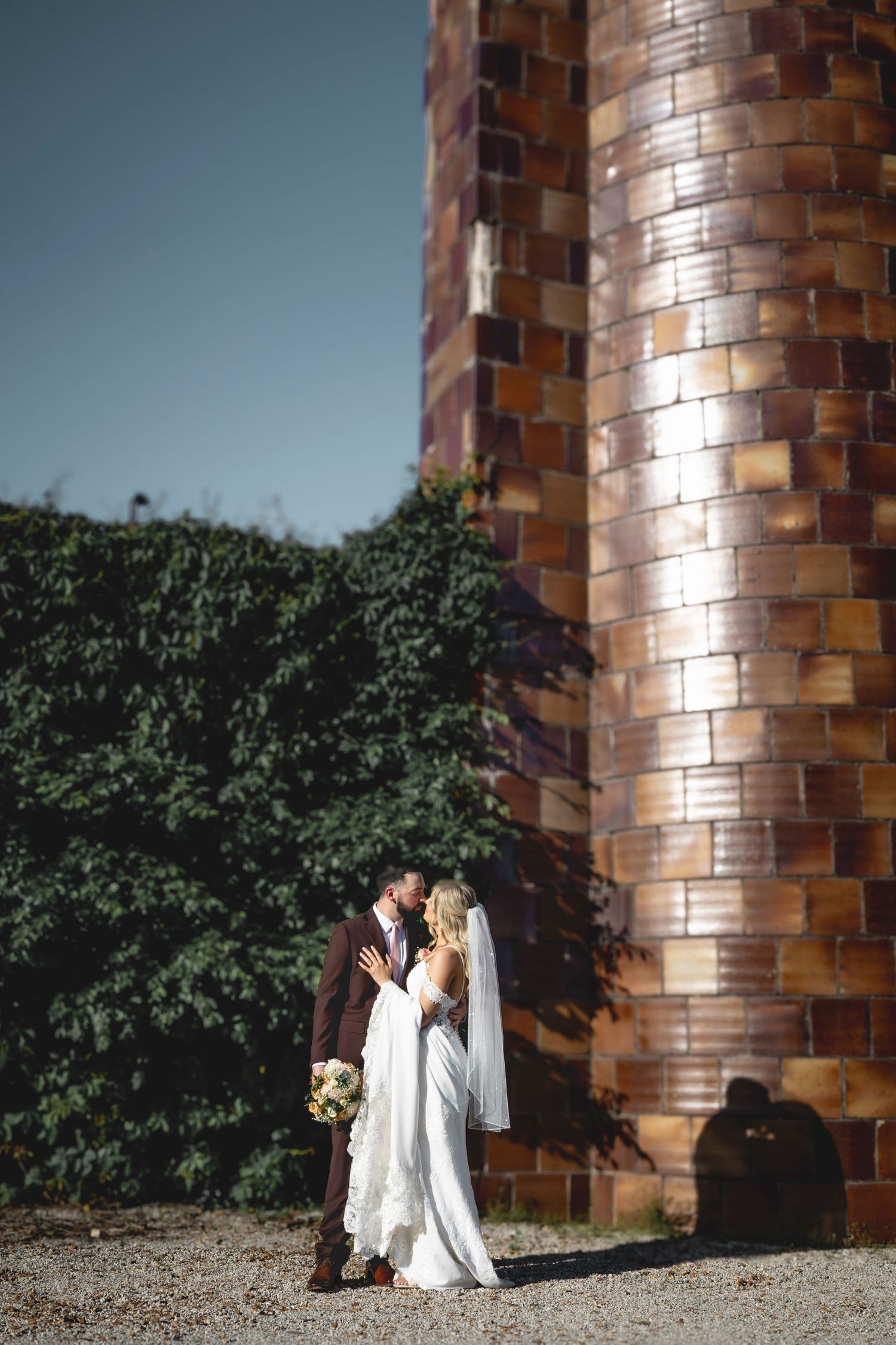 A romantic wedding photo sequence against a brick wall and greenery in natural lighting.