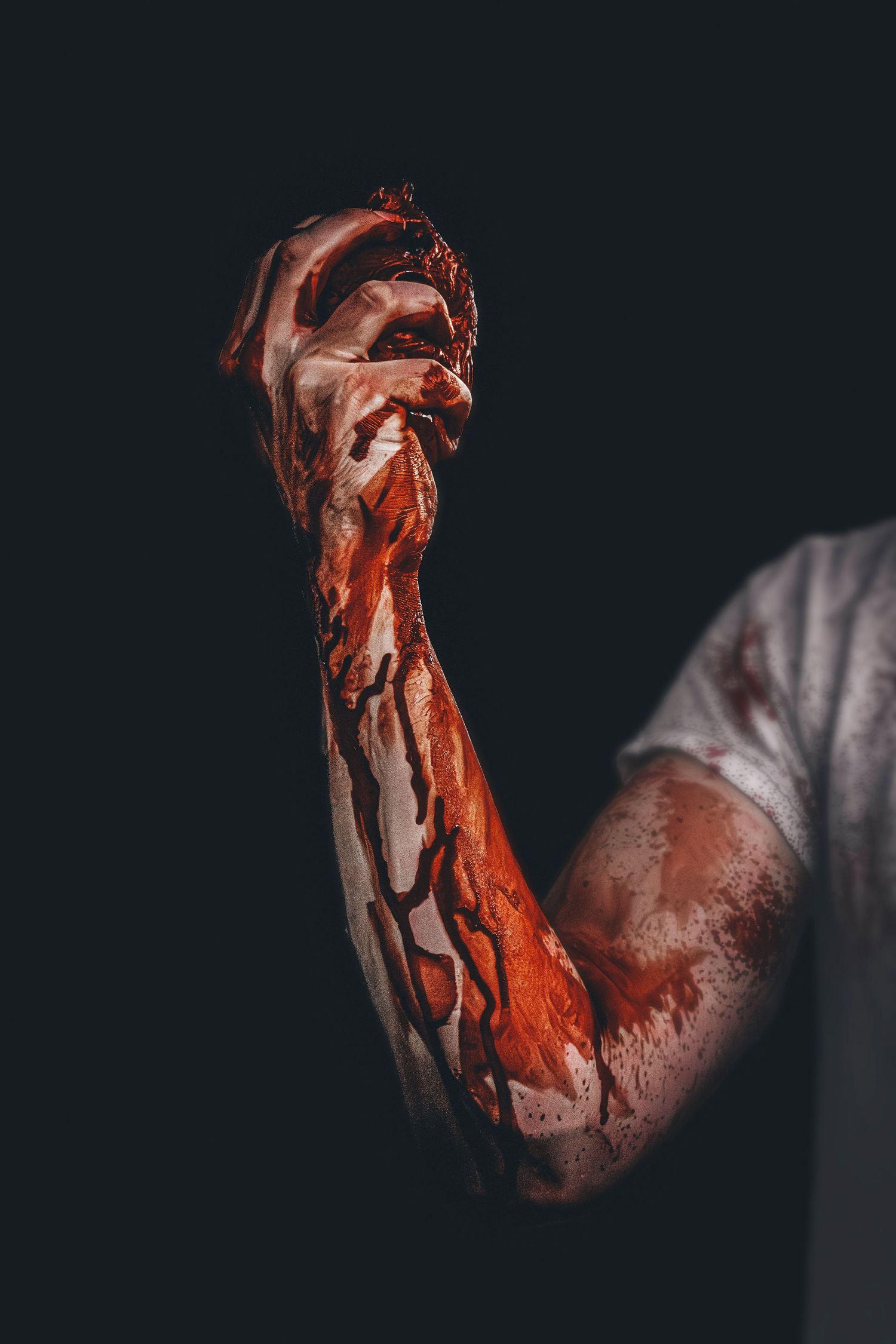 Dramatic photo of blood-covered hands against dark background.