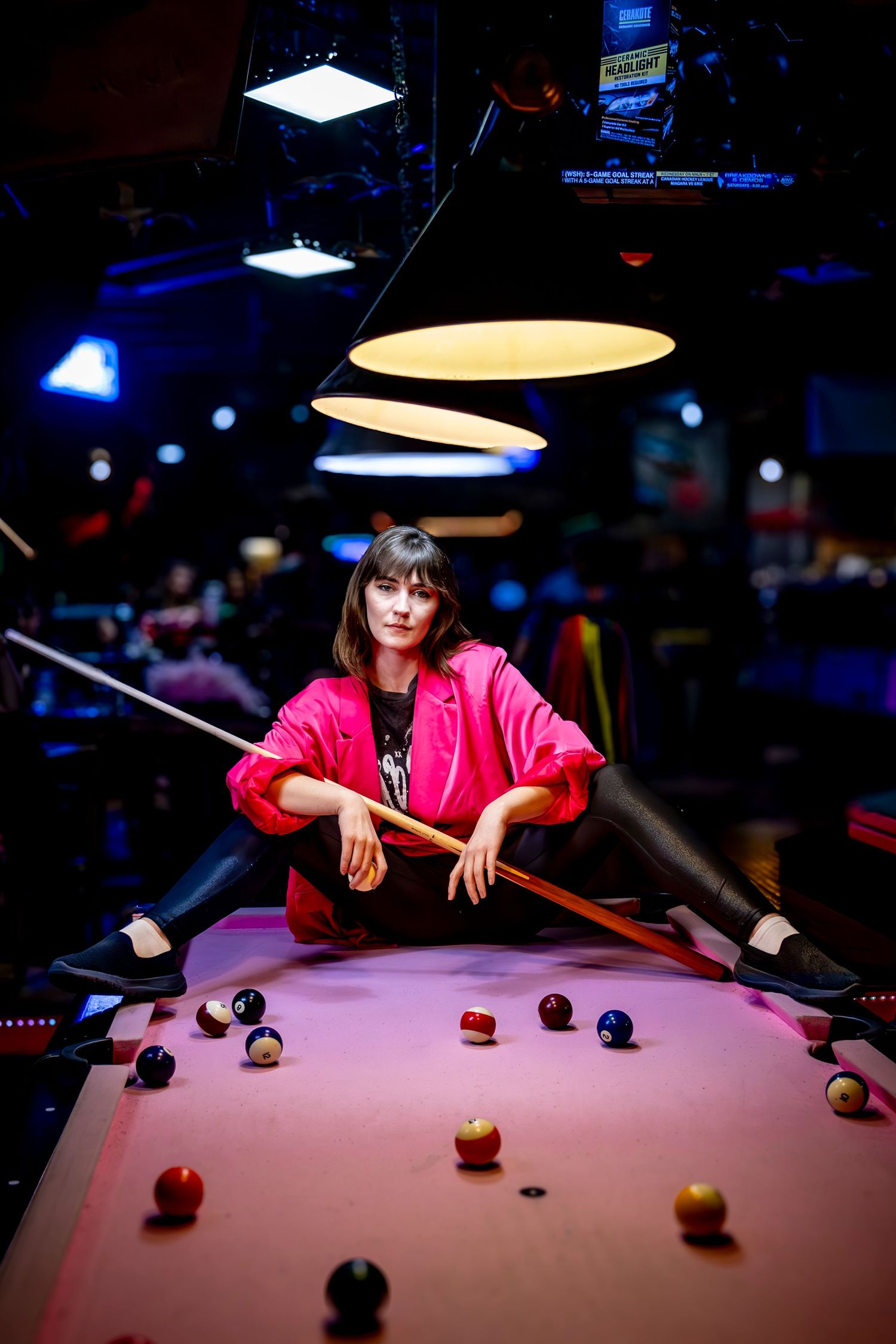 Dramatic pool hall scene with red jacket and billiard balls on pink-lit table.