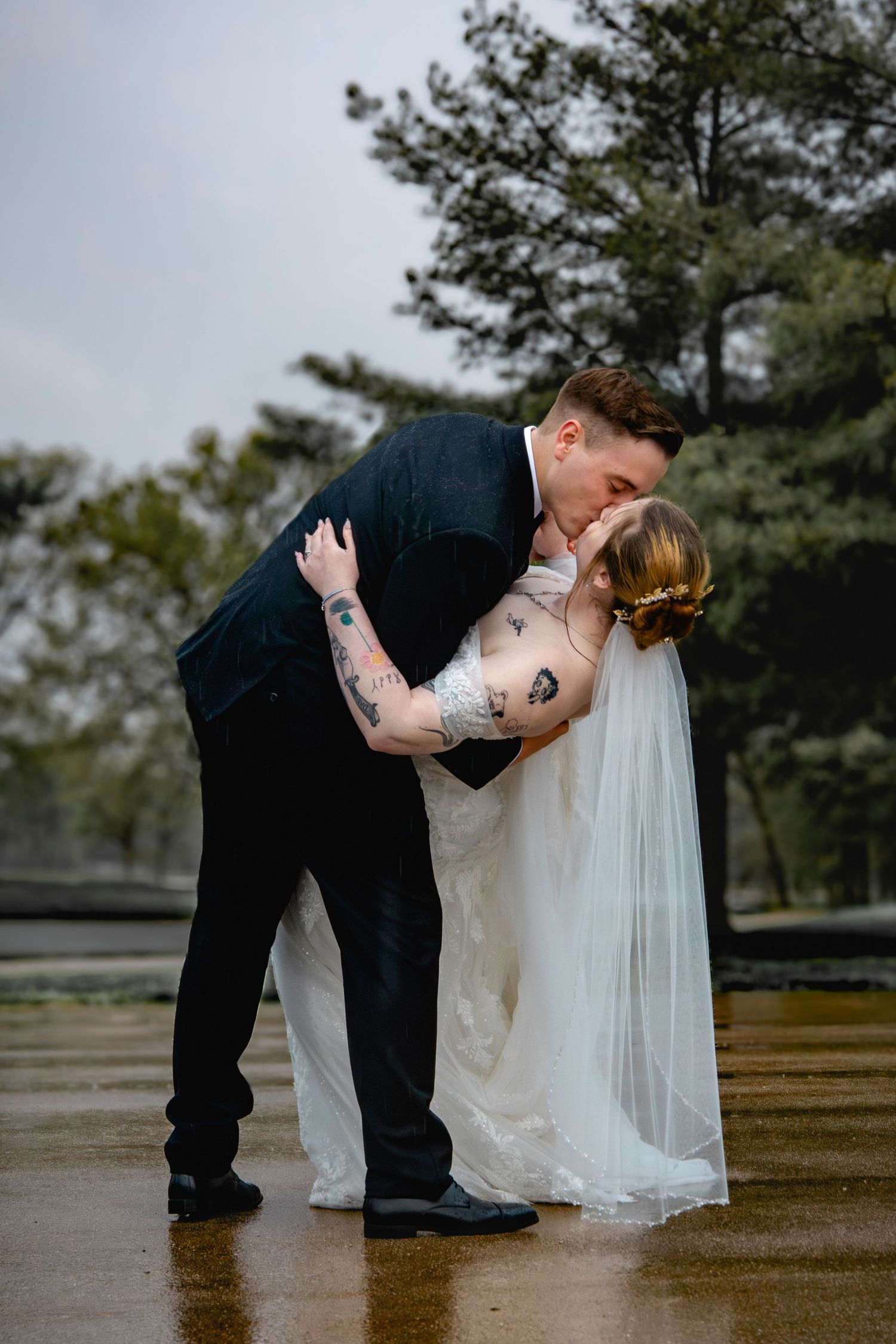 A romantic dip pose between newlyweds on their wedding day outdoors.