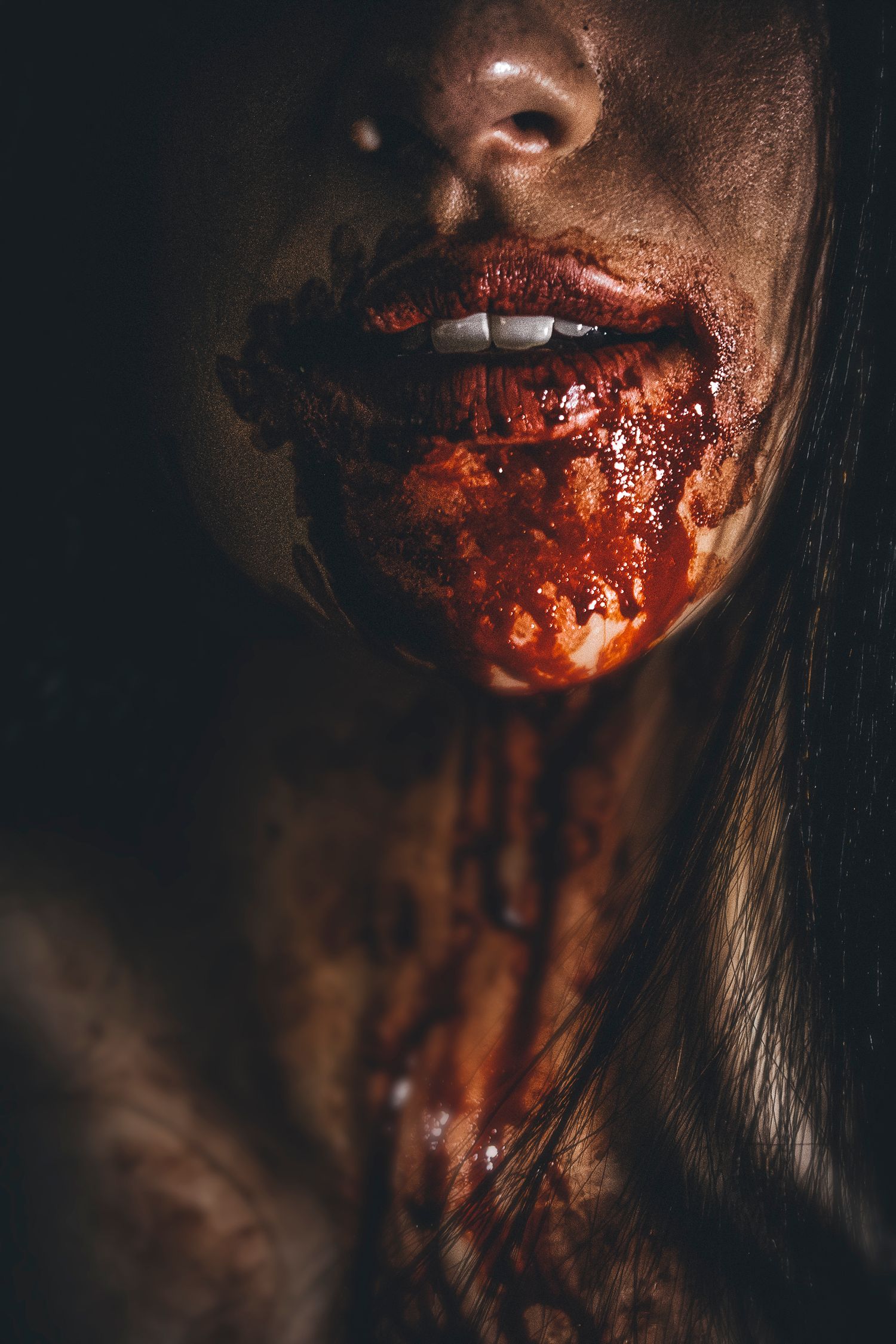 Close-up artistic portrait with dark dramatic lighting and red special effects makeup.