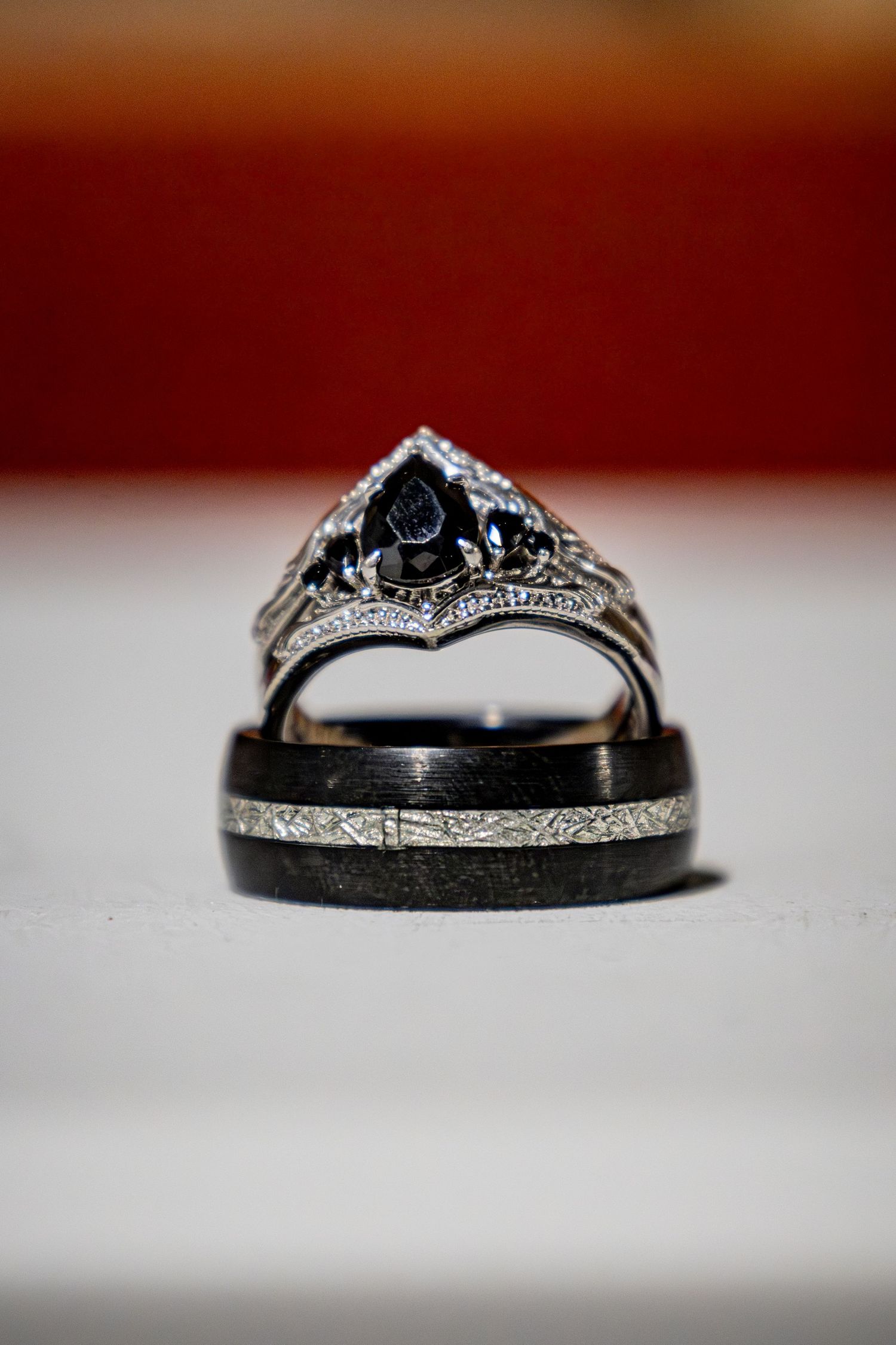 Close-up of wedding rings with intricate details on white surface.