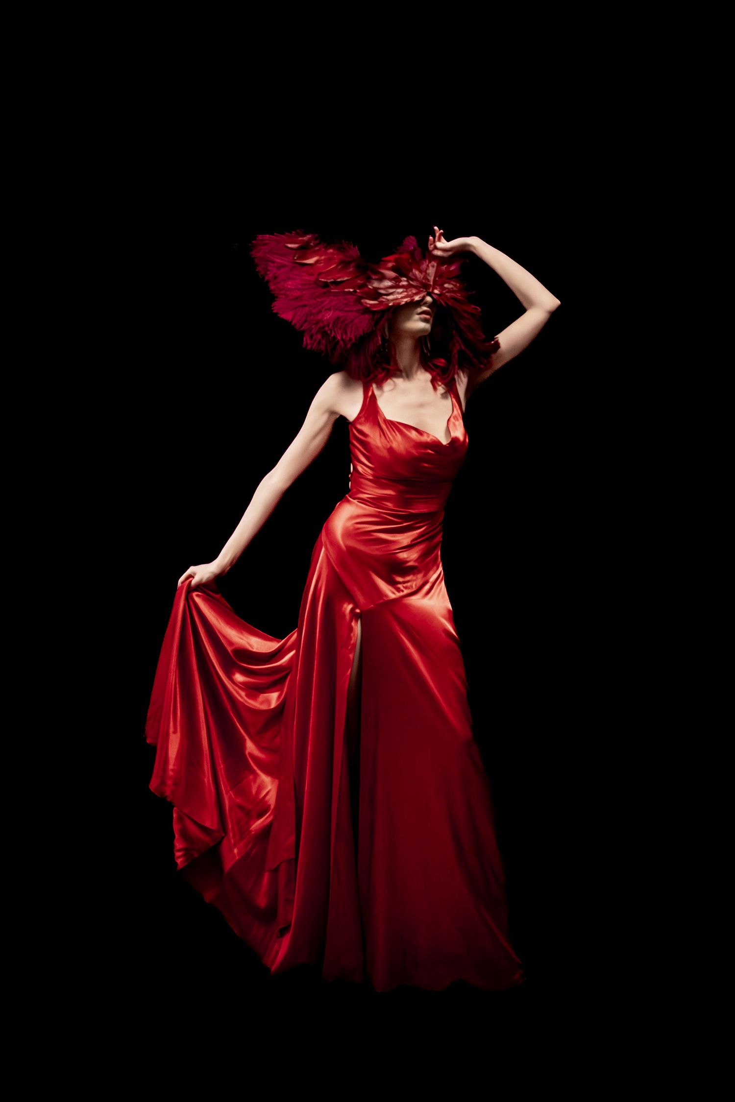 Flowing red satin dress movement captured against black background in dramatic style.