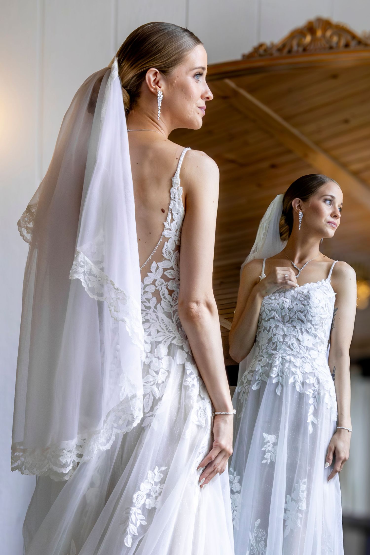 Elegant lace wedding dress with flowing veil photographed in window light.