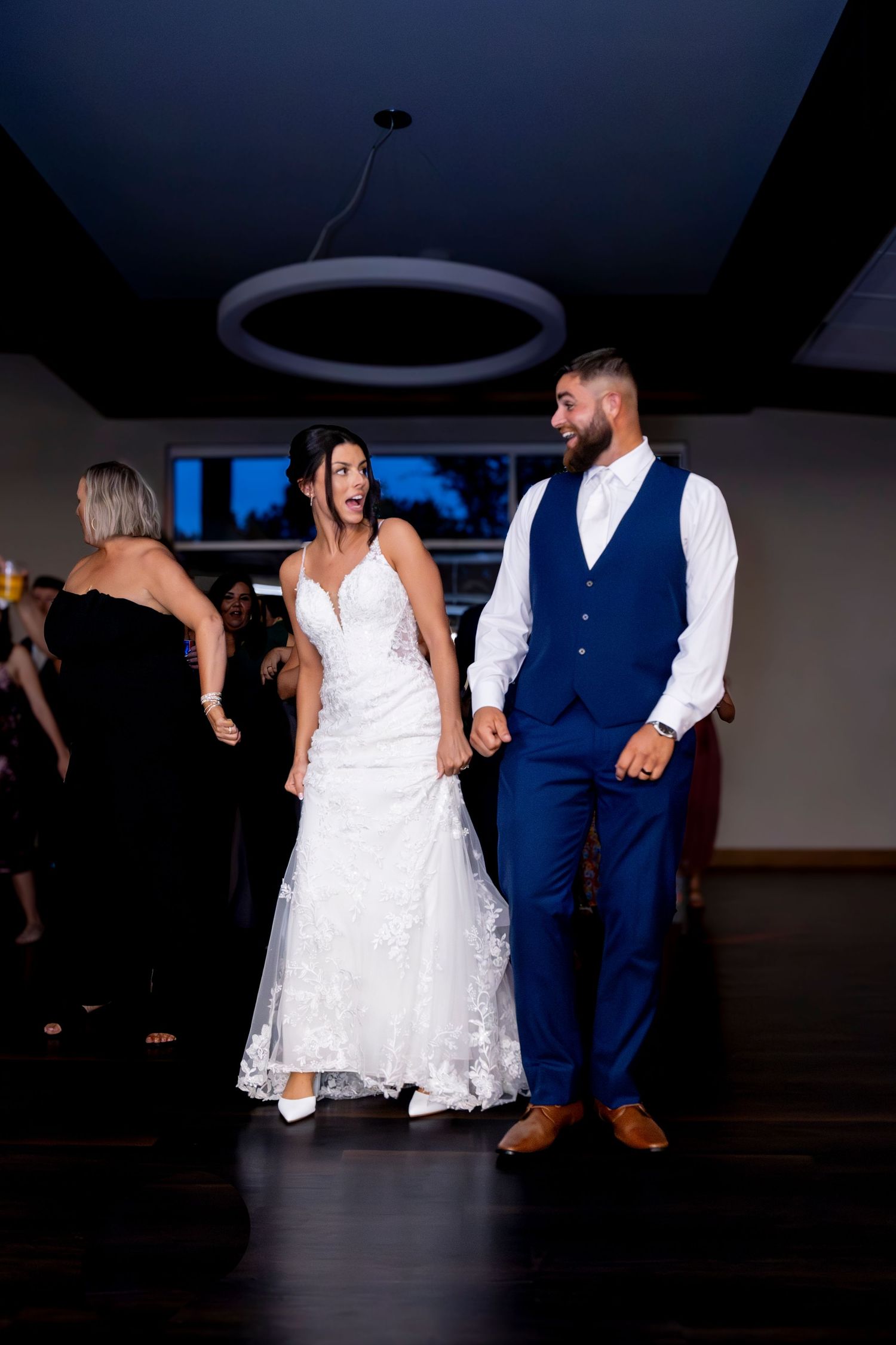 Wedding couple dances energetically in darkened reception venue.