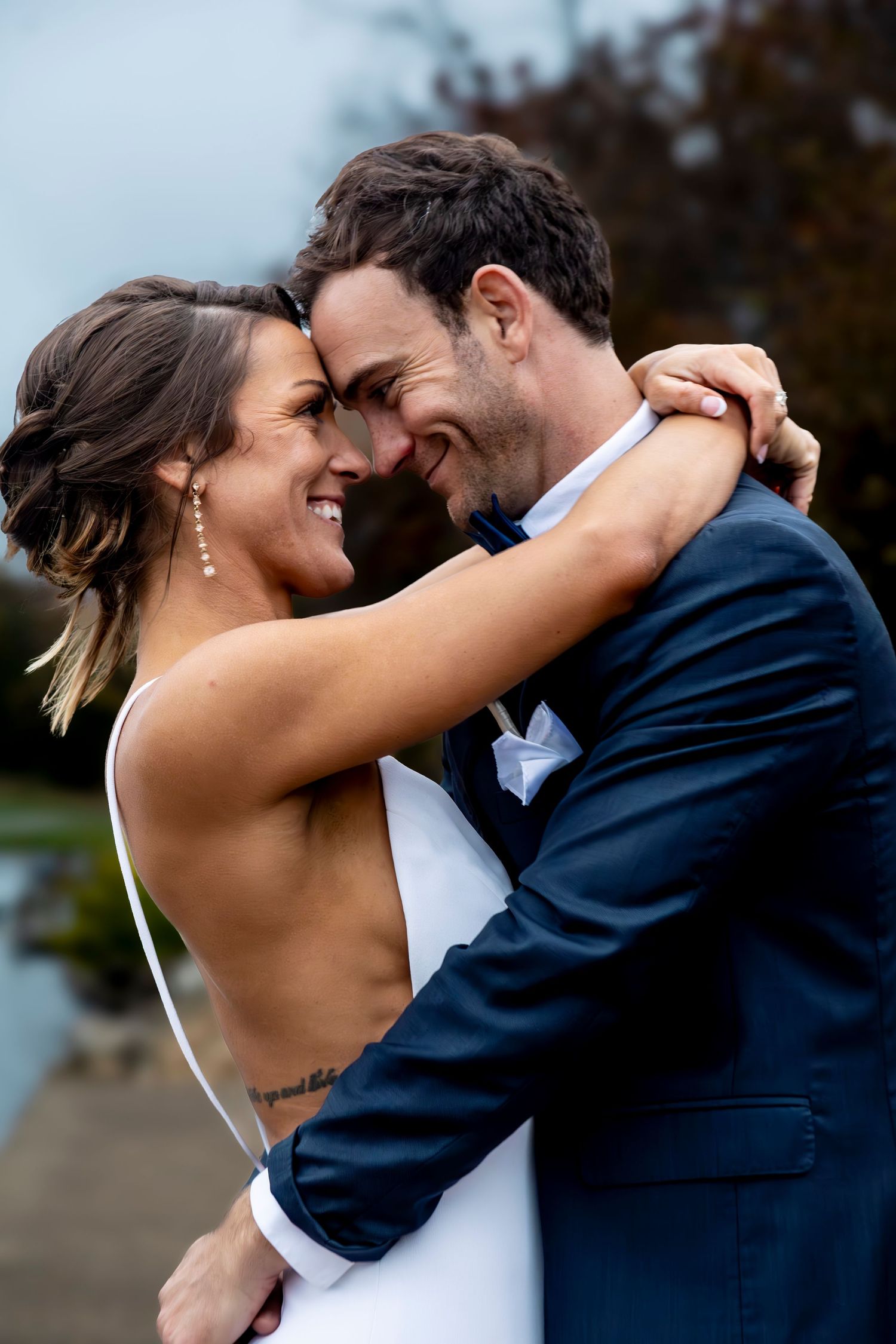 A romantic wedding kiss sequence between newlyweds in formal attire by the waterfront.