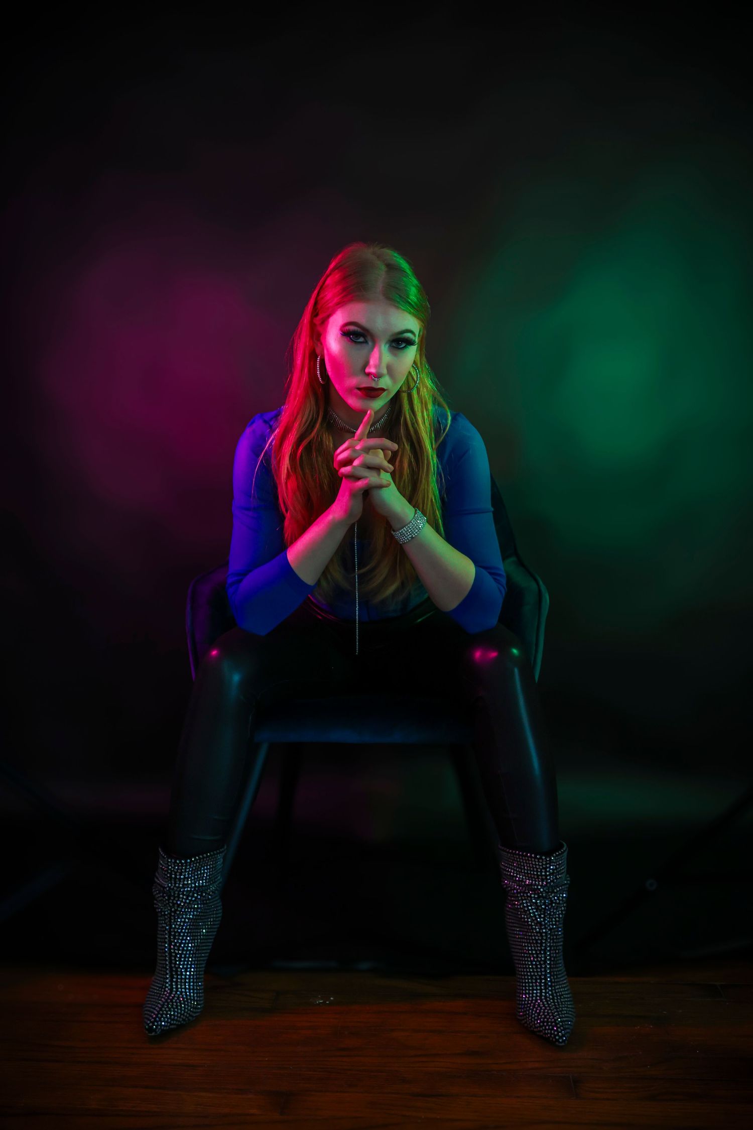 Artistic portrait series with dramatic colorful lighting showing a figure seated in darkness against vibrant blue and red hues.