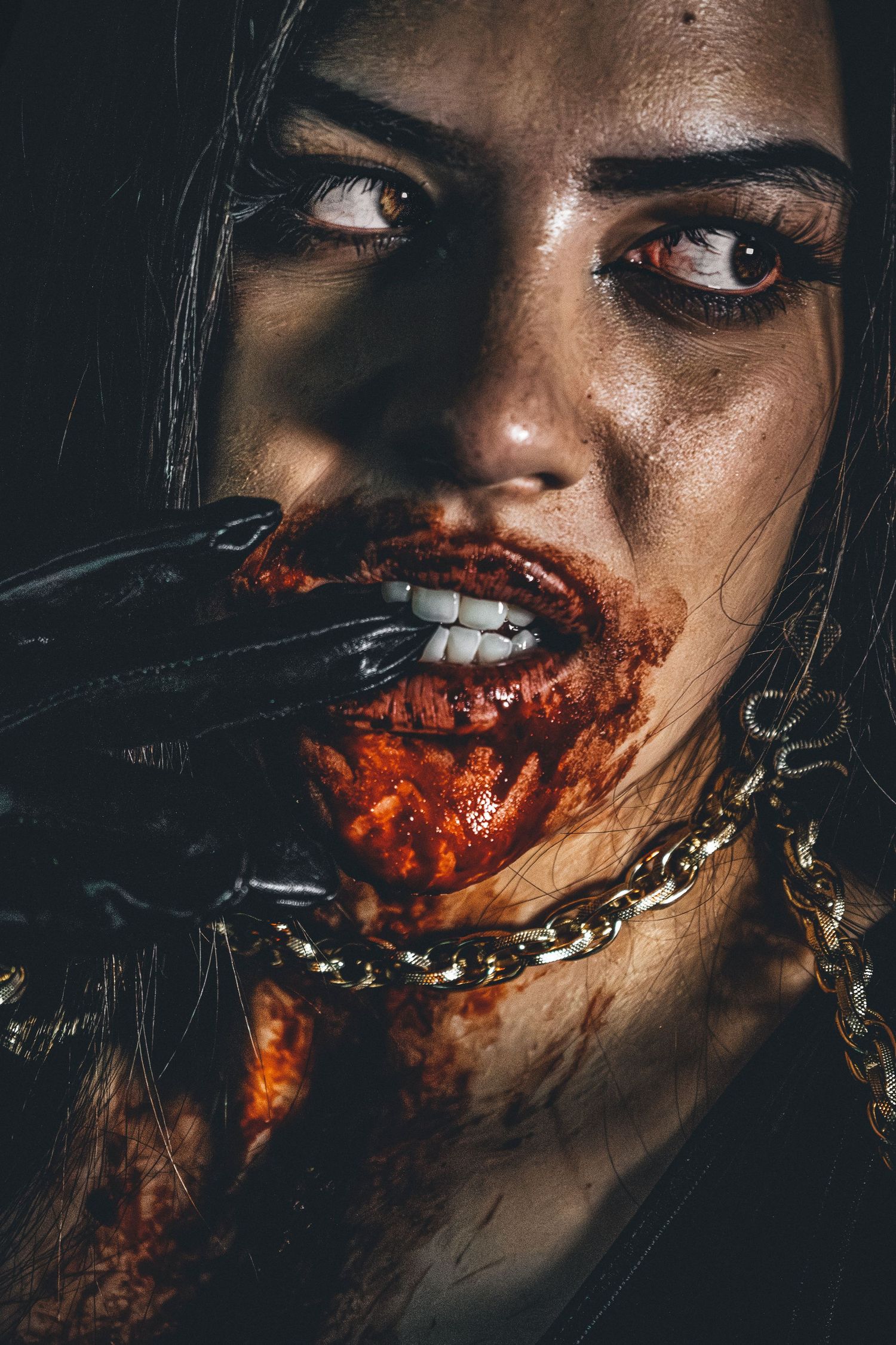 Close-up dramatic portrait with theatrical blood makeup in dark lighting.
