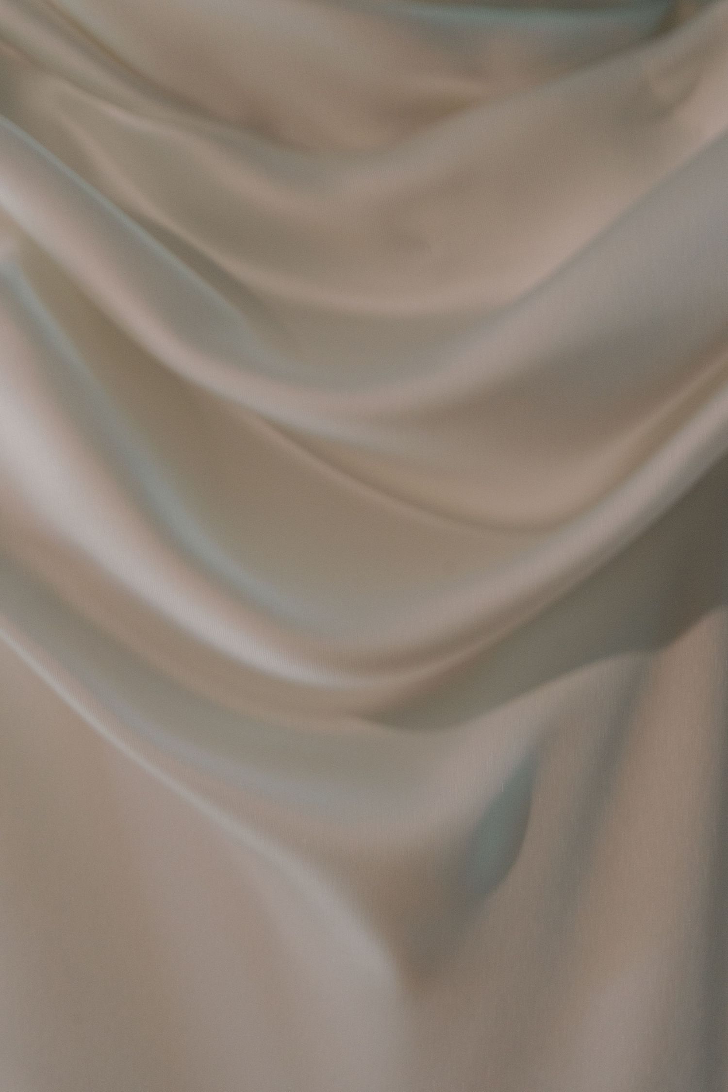 Close-up details of ivory satin fabric with elegant draping and folds.