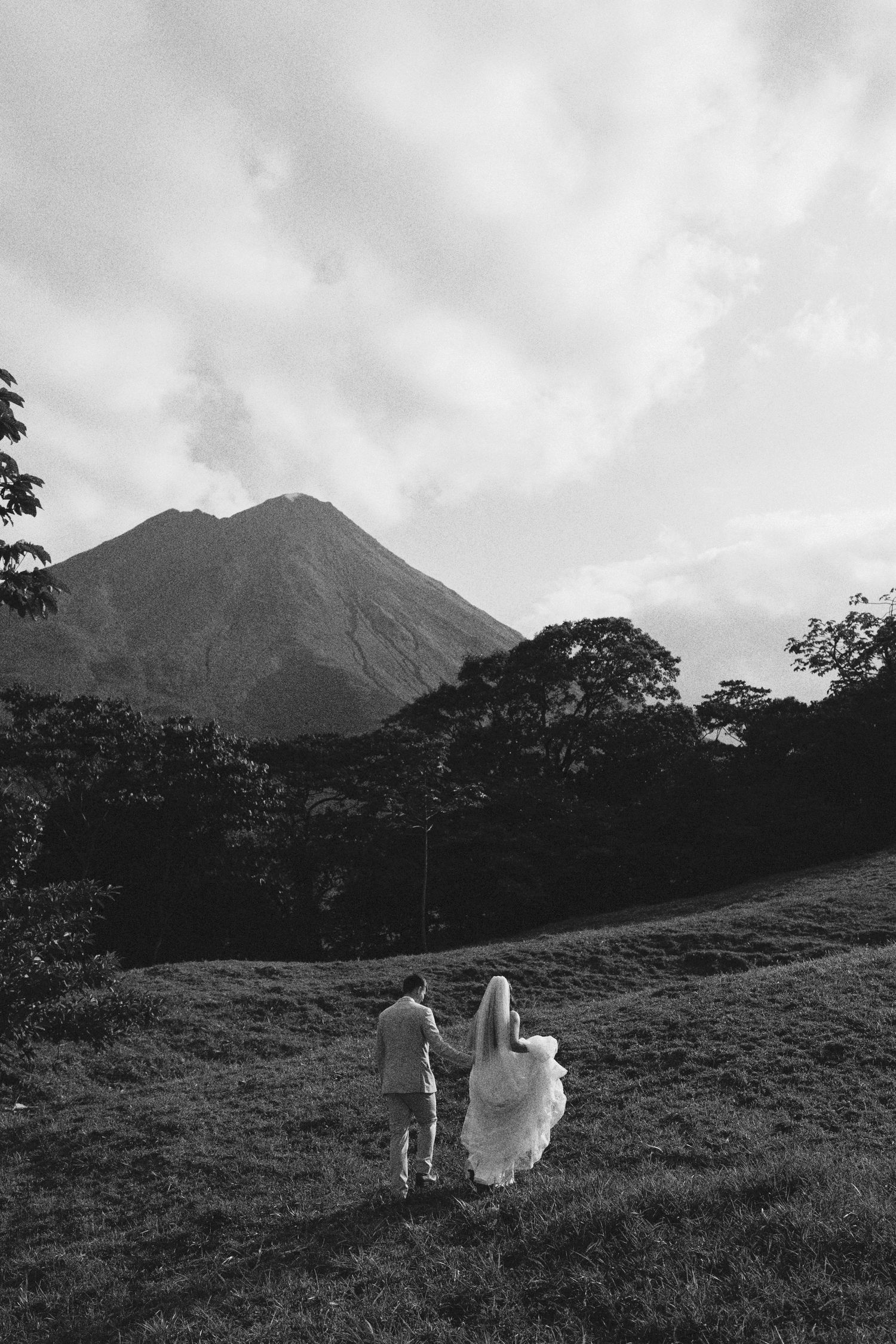 Silhouetted figures on a hillside with dramatic mountain peaks in black and white.