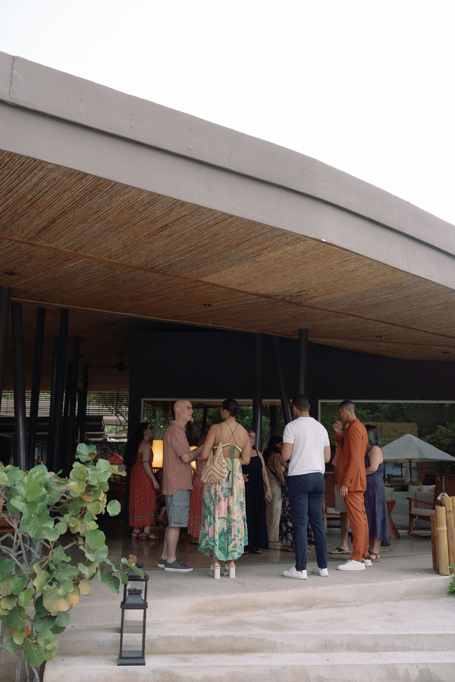 People gathered in line under a modern covered walkway with bamboo ceiling details.