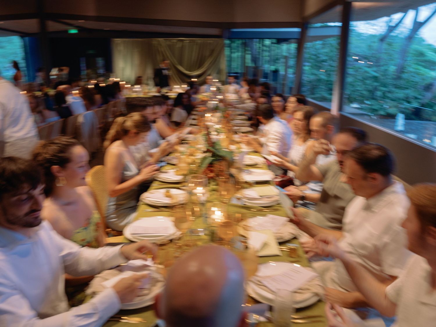 Wedding reception dinner with guests seated at long tables in an outdoor setting.