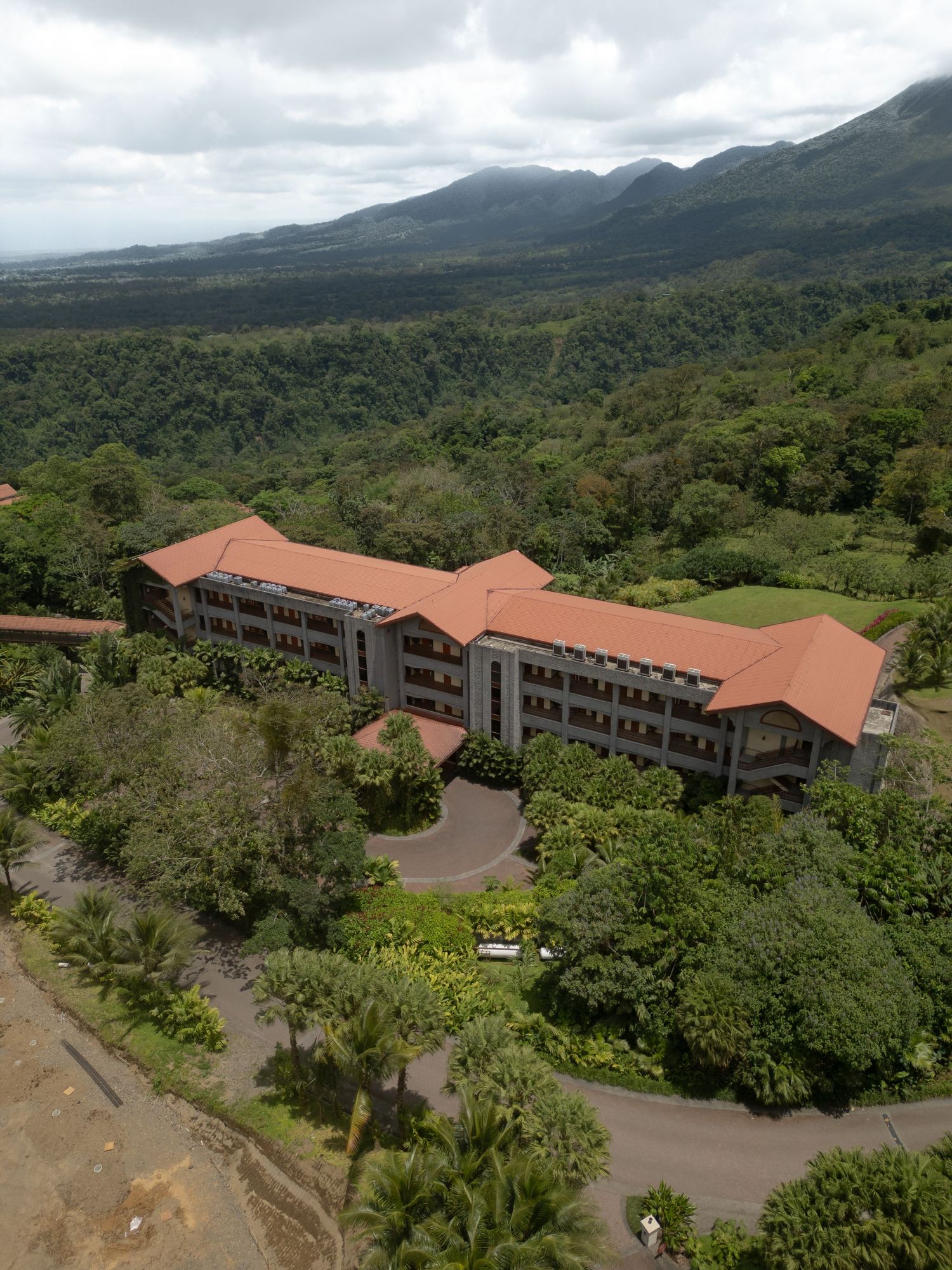 Aerial view of a luxury resort nestled in lush mountain landscape with terracotta roofs.