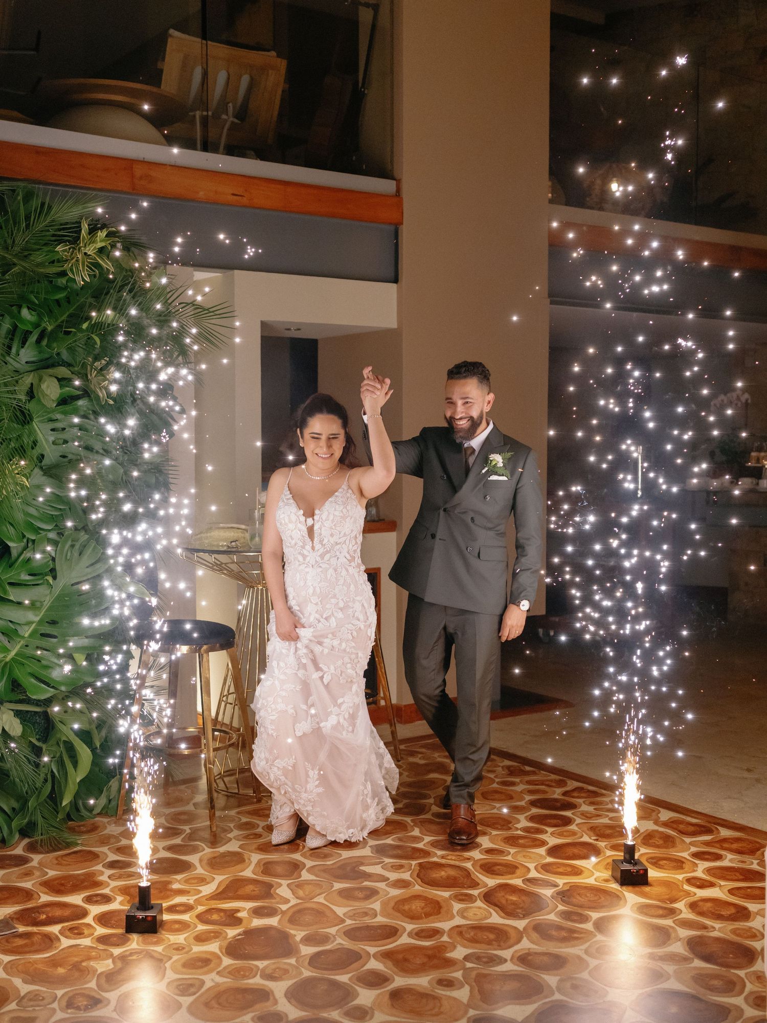 Wedding couple dances under sparkling lights on a patterned floor.
