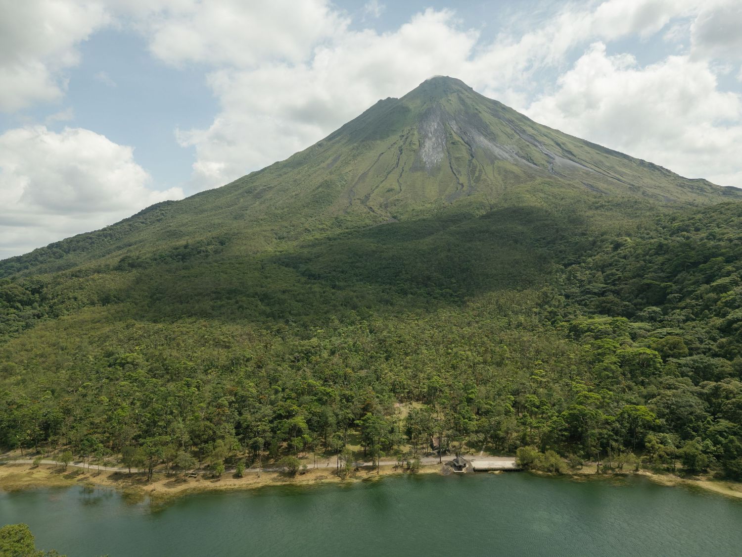 Panoramic view of a majestic green mountain with a lake at its base.