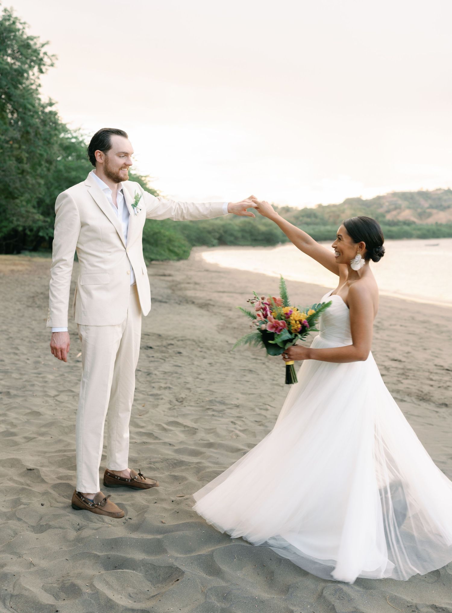 Playful beach wedding sequence showing a couple dancing and twirling in the sand.